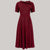 A 1940s vintage style short sleeve dress with a side tie-neck and a tie-waist belt. This dress is in a burgundy colour and has a a-line skirt and is designed to finish below the knee.