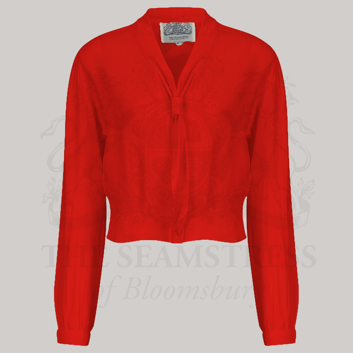 A 1940s sailor style blouse with long sleeves in red. Featuring a roll style collar to give the iconic sailor look. Small buttons run down the front of the blouse for fastening but are hidden by the long collar.