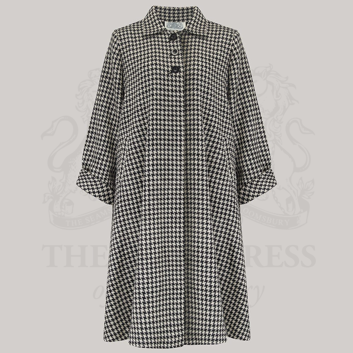 A 1940s style 43 inch long swing jacket. The jacket is in black and white houndstooth print, has three buttons at the top front, small shoulder pads, and is lined in satin. 