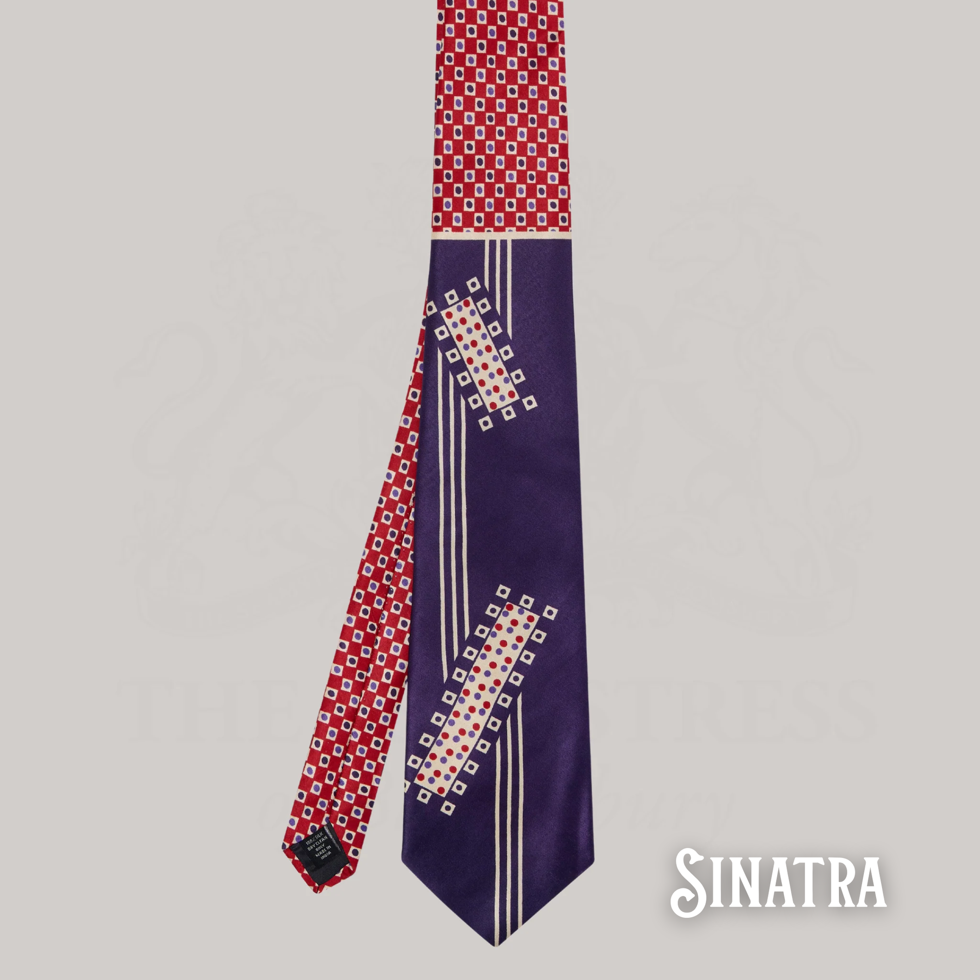 Navy tie with red and white geometric pattern on a gray background