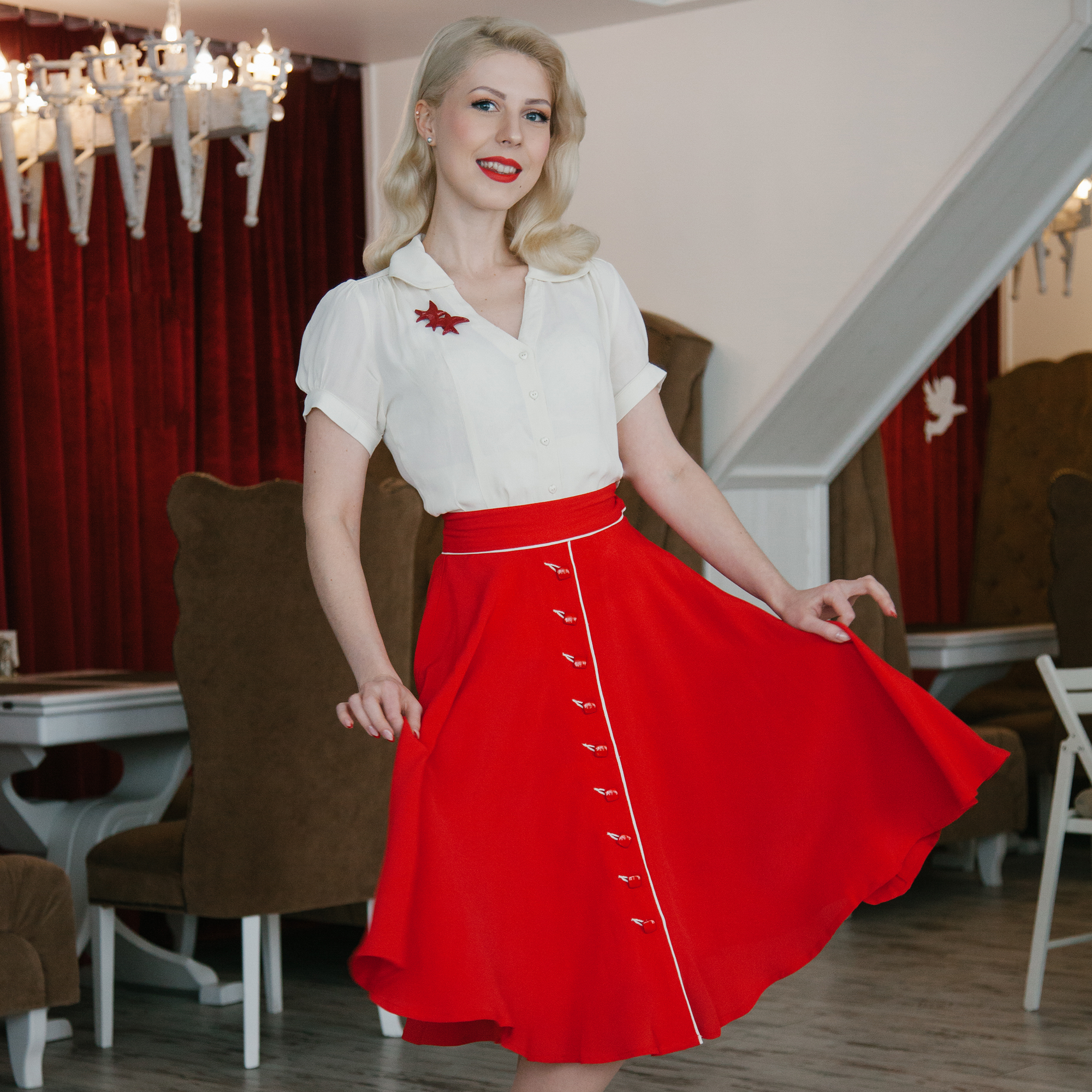 A woman wearing a red vintage dancing skirt, paired with a cream blouse and matching red accessories.