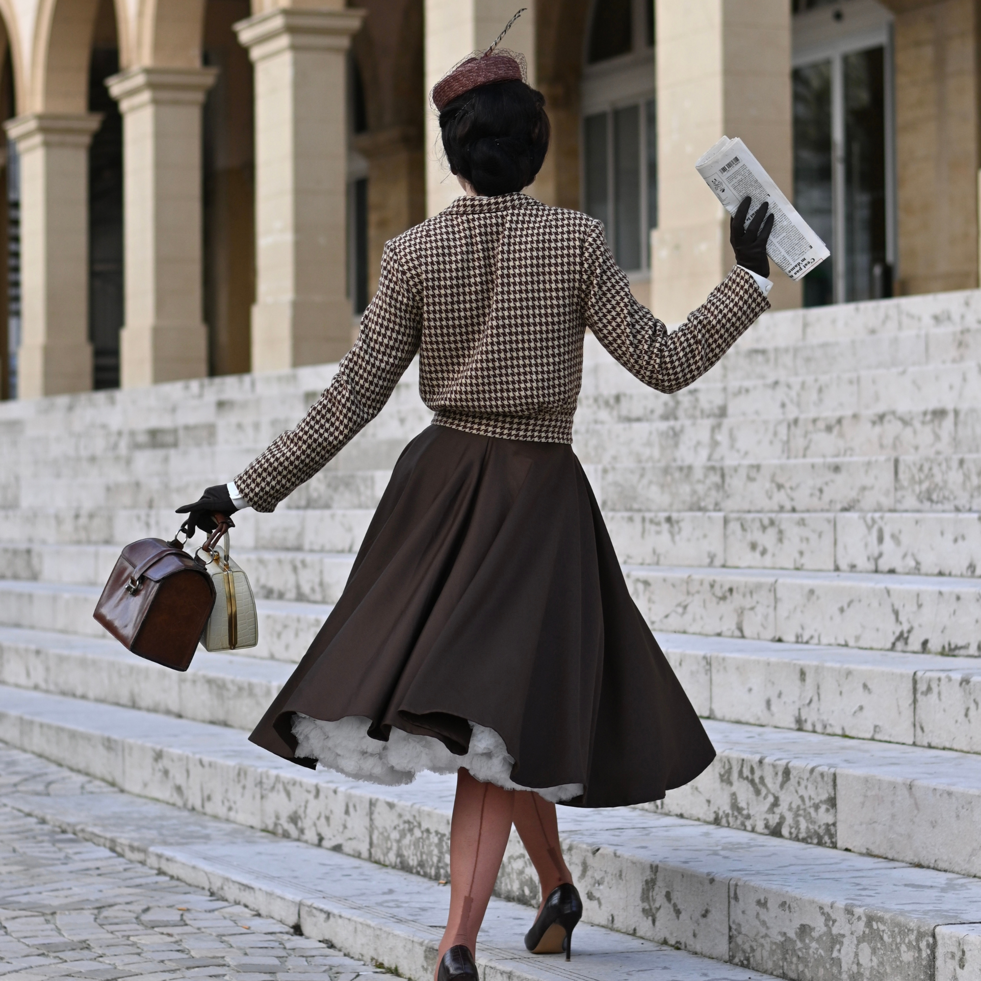 Woman in vintage outfit walking up stone steps in an urban setting