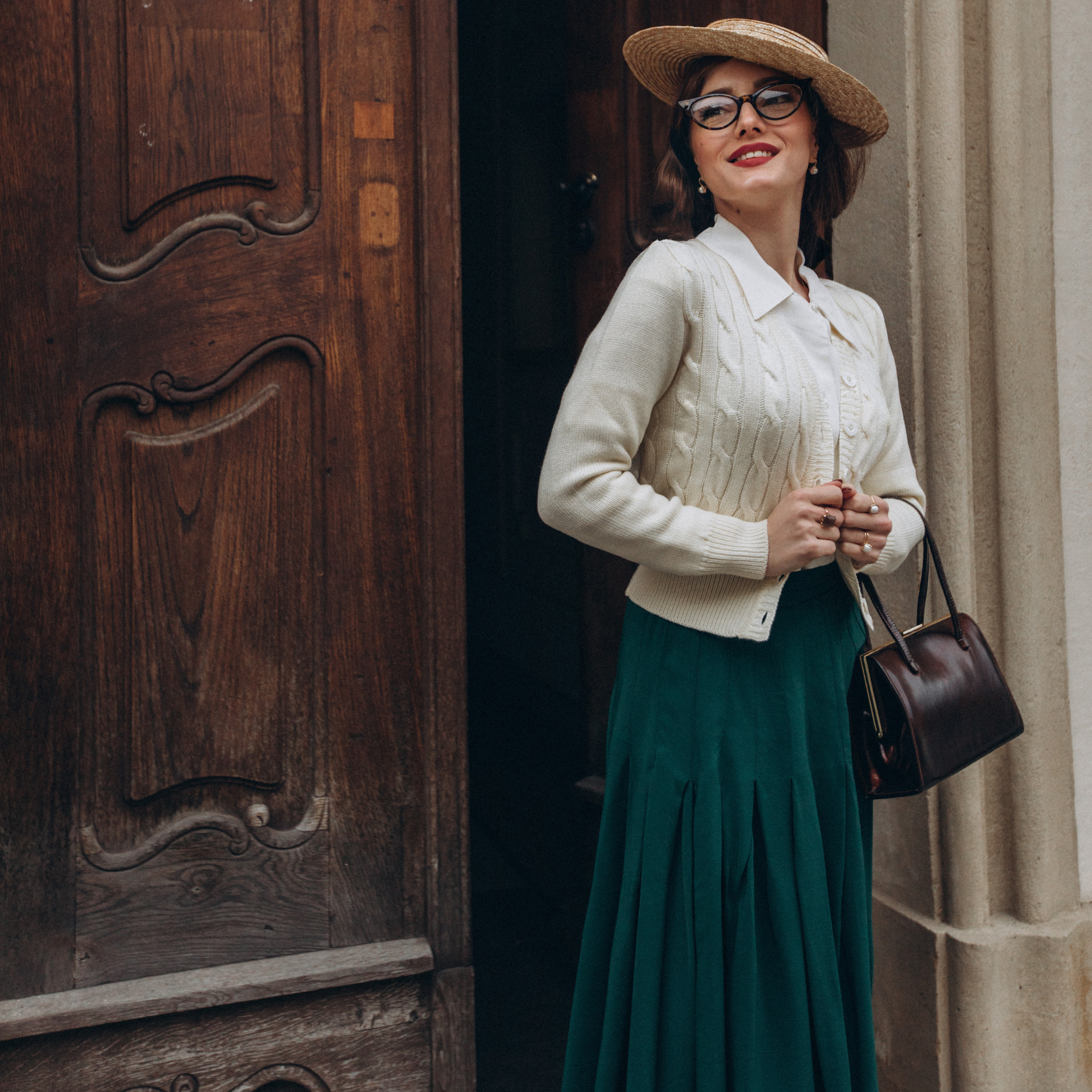 Model wears a 1940s style cable knitted cardigan in cream, curled vintage style hair with a matching cream beret. Matching cream buttons feature down the front of the cardigan.
