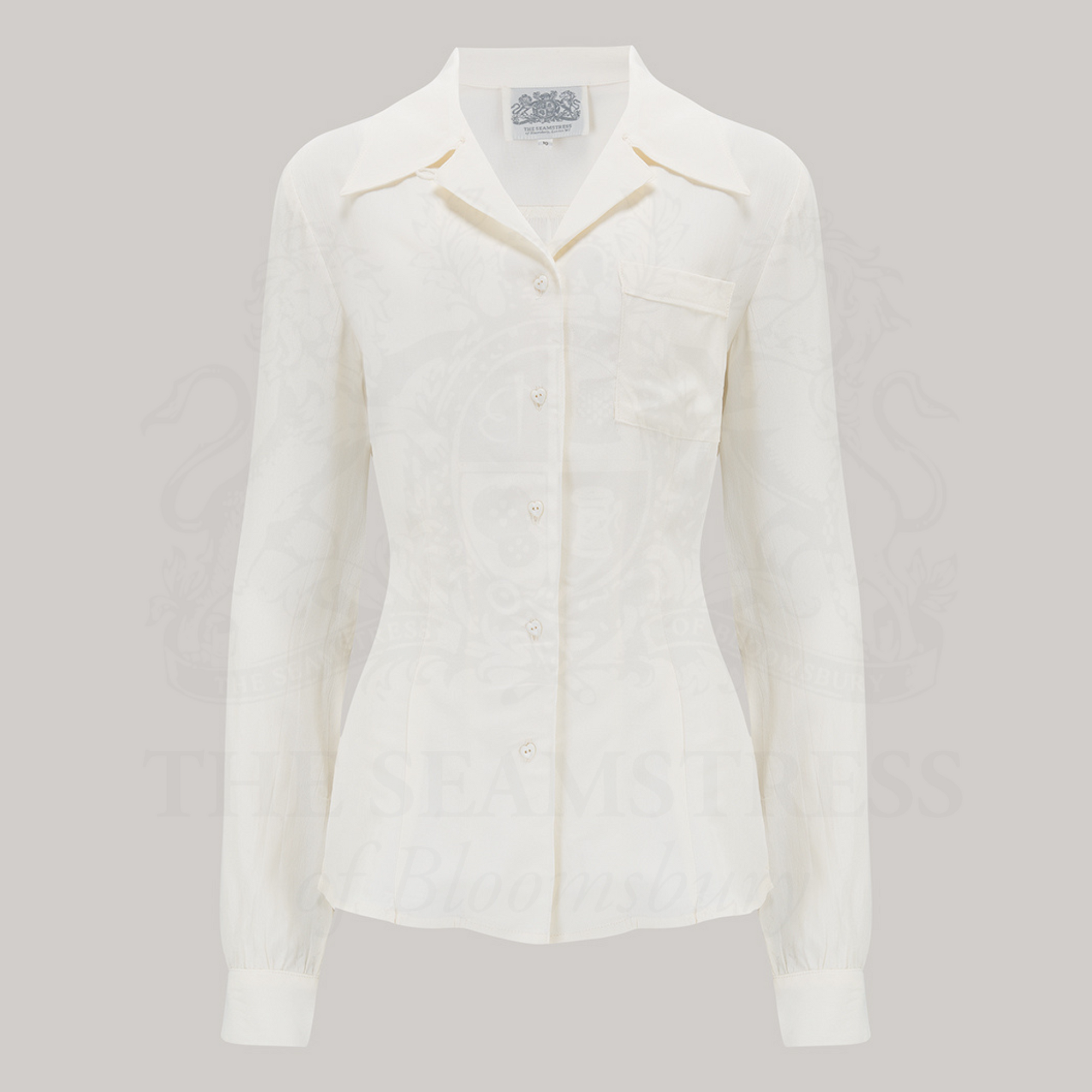 A cream-colored blouse with long sleeves, featuring a convertible collar with a hidden button