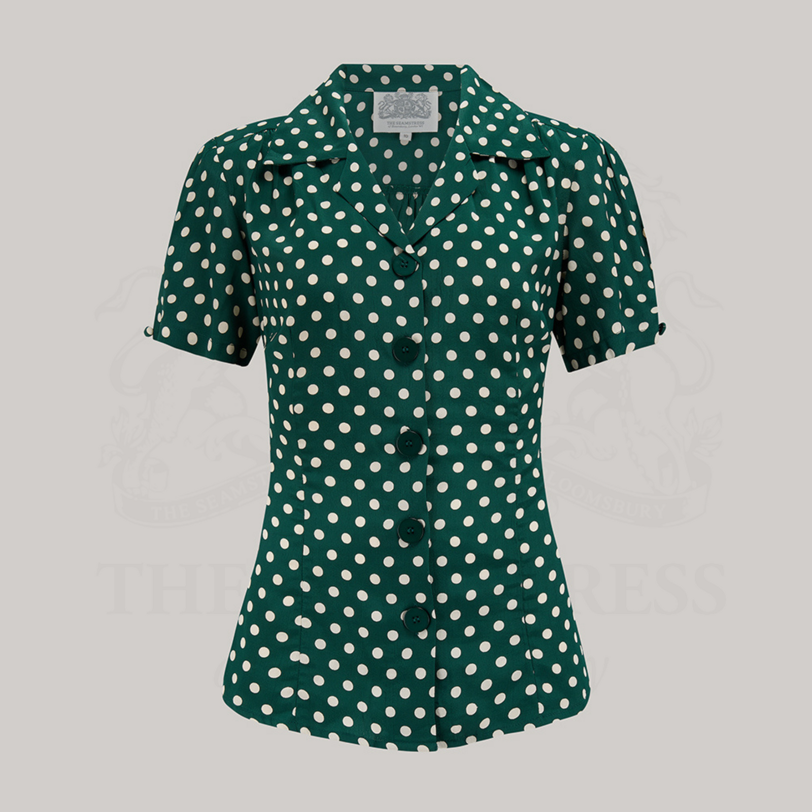 A green polka dot blouse with a classic revere collar, large bakelite buttons, and short sleeves.