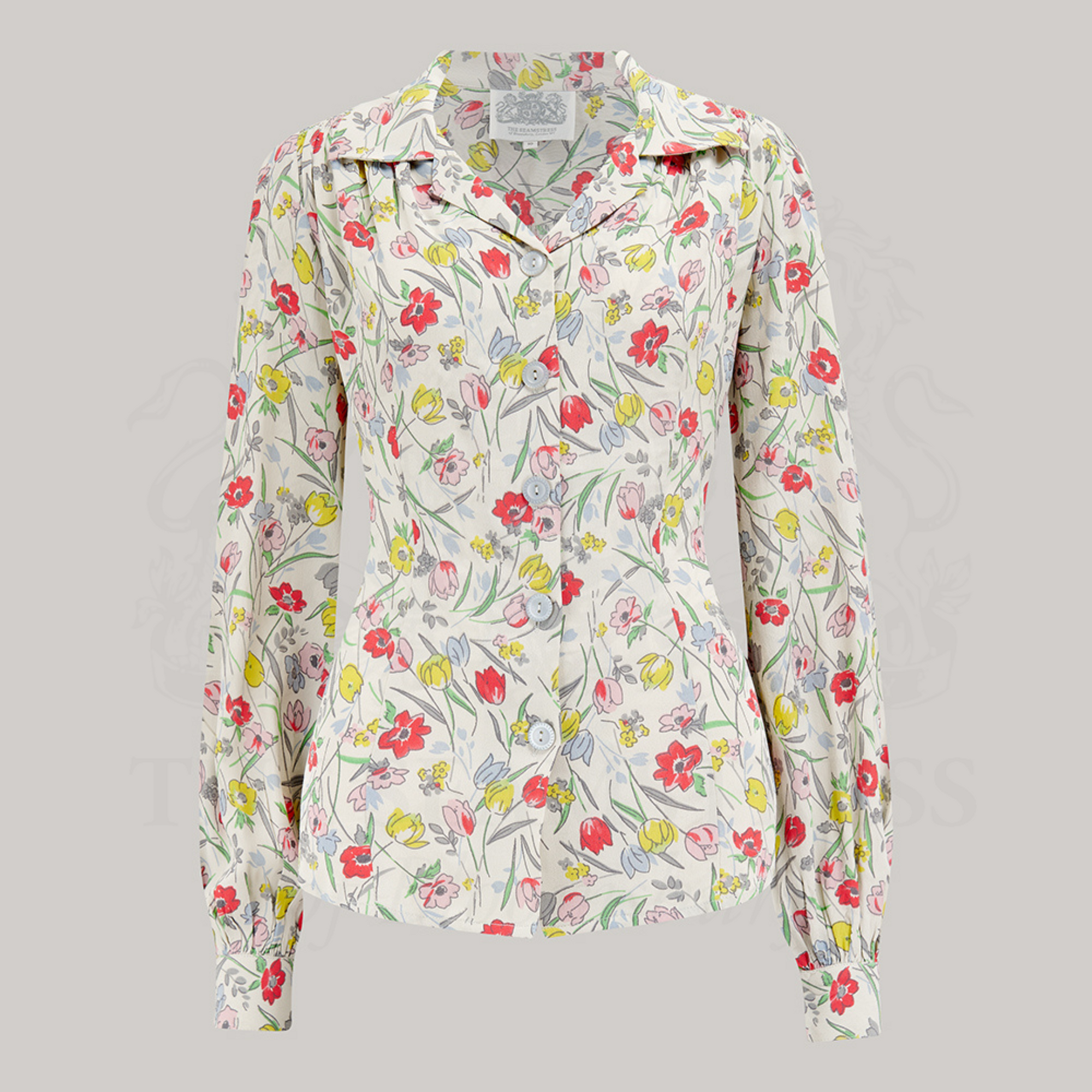 A vintage style blouse with a revere collar, long sleeves with full cuffs, and a fitted waist, printed with a floral pattern.