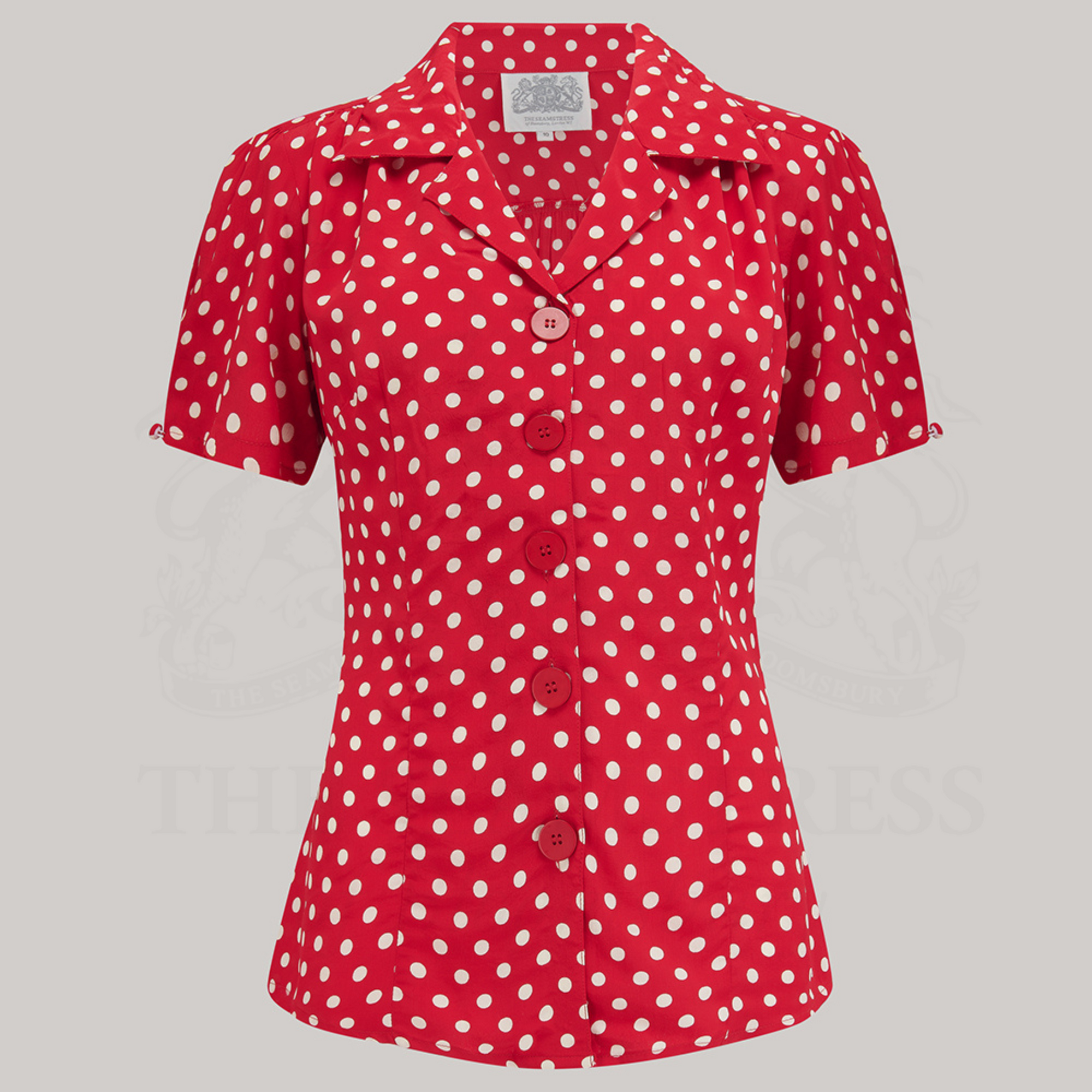 A red polka dot blouse with a classic revere collar, large bakelite buttons, and short sleeves.
