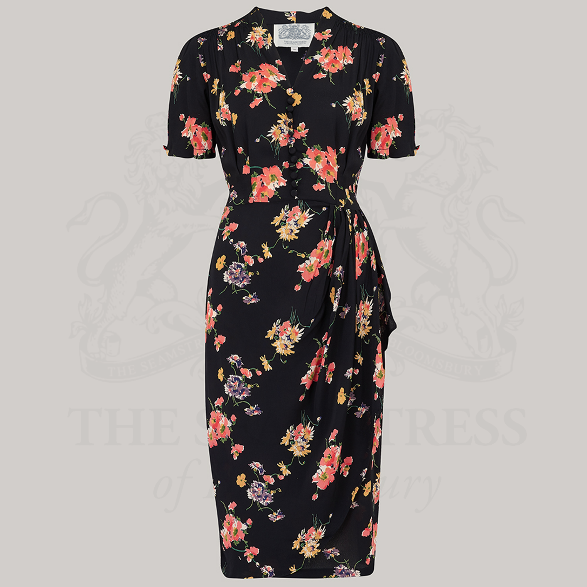 A black floral dress with a waterfall ruffle on the waist, decorative buttons on the front bodice, and short sleeves.