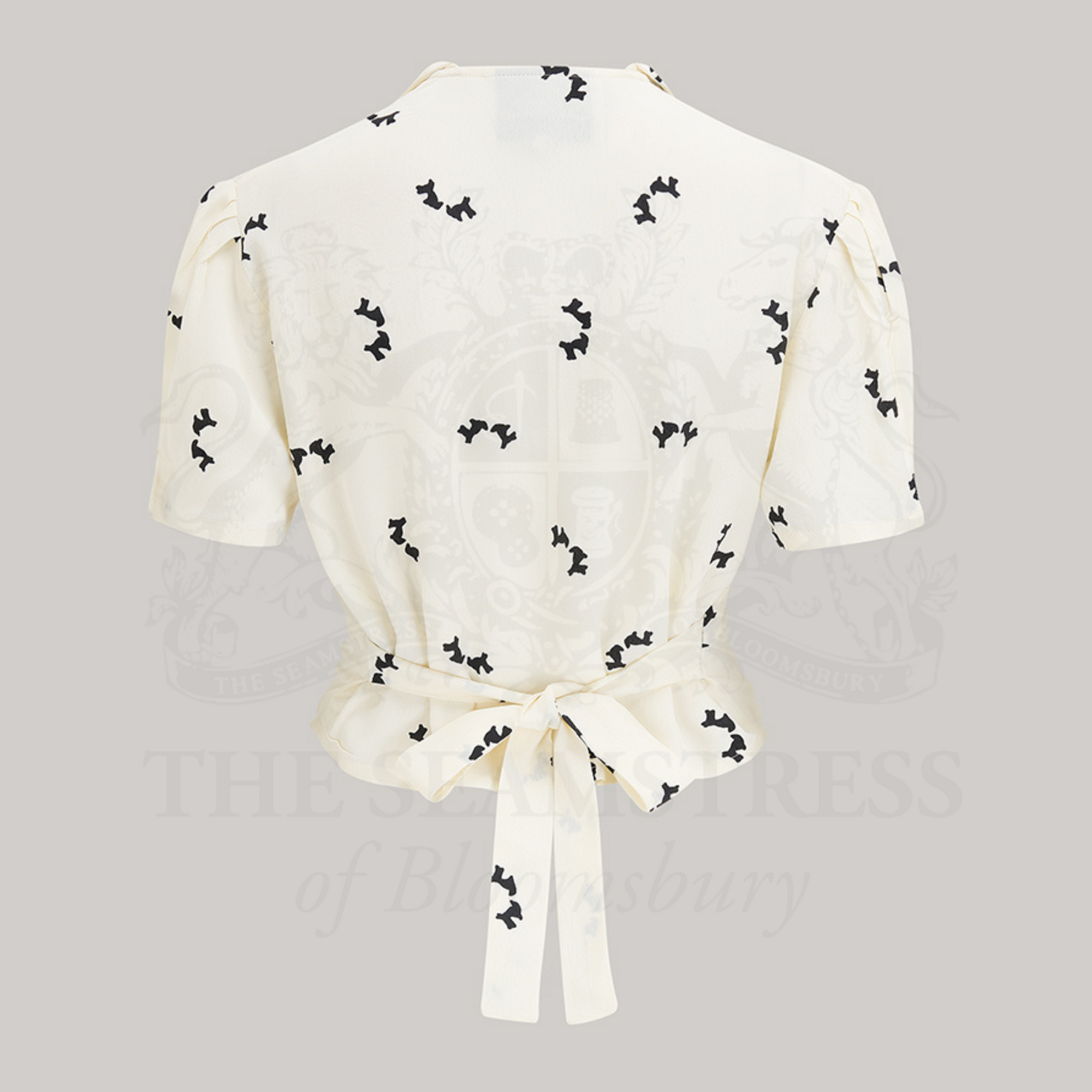 1940s style short sleeve blouse. The blouse is cream coloured with small black dogs dotted around the blouse. 