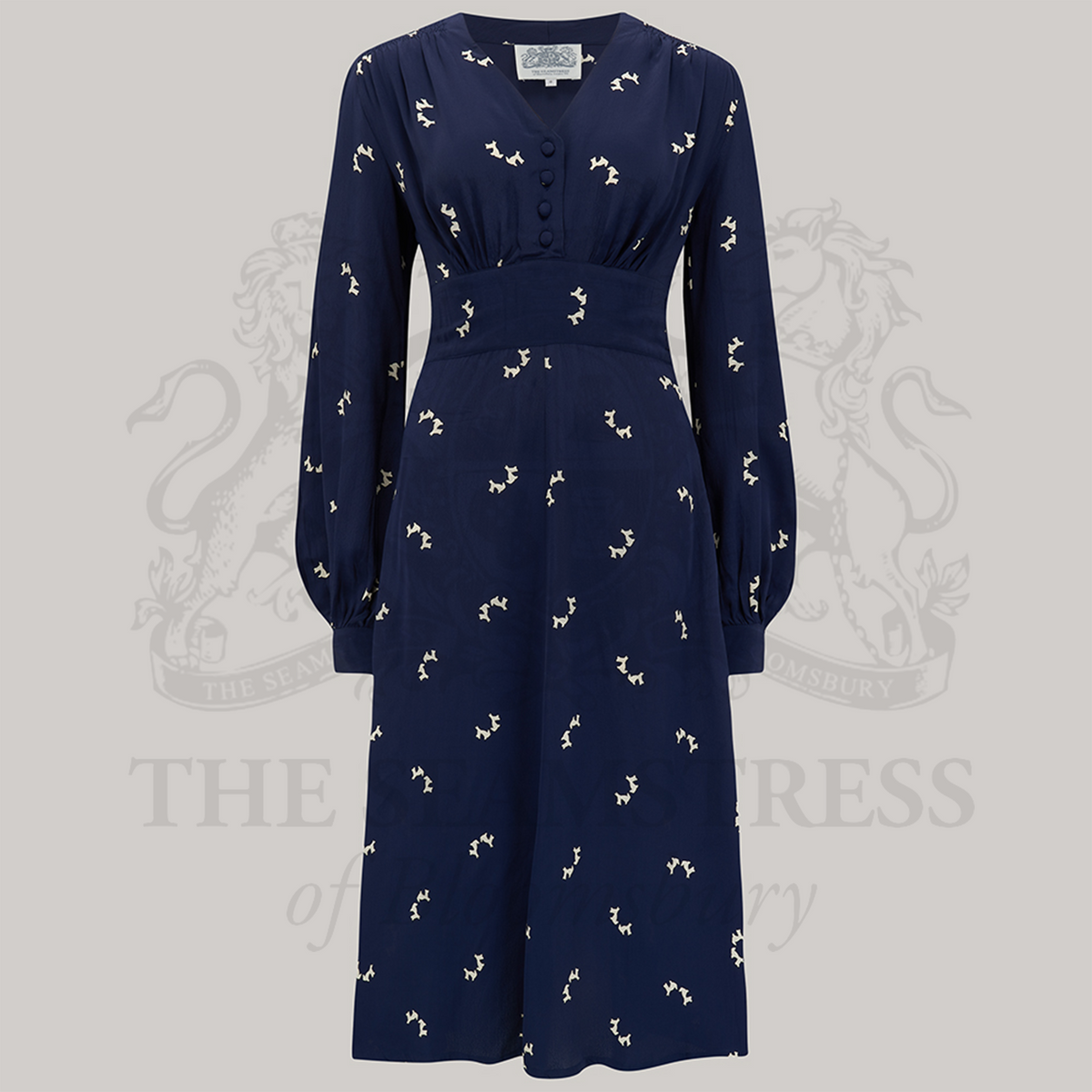 A 1940s style long sleeve dress in navy with small scotty dogs. Featuring gauged-in top yoke detailing on the shoulders and sleeves that puff out fully at the cuff. 4 small buttons down the front of the dress, and a tie-waist belt. 