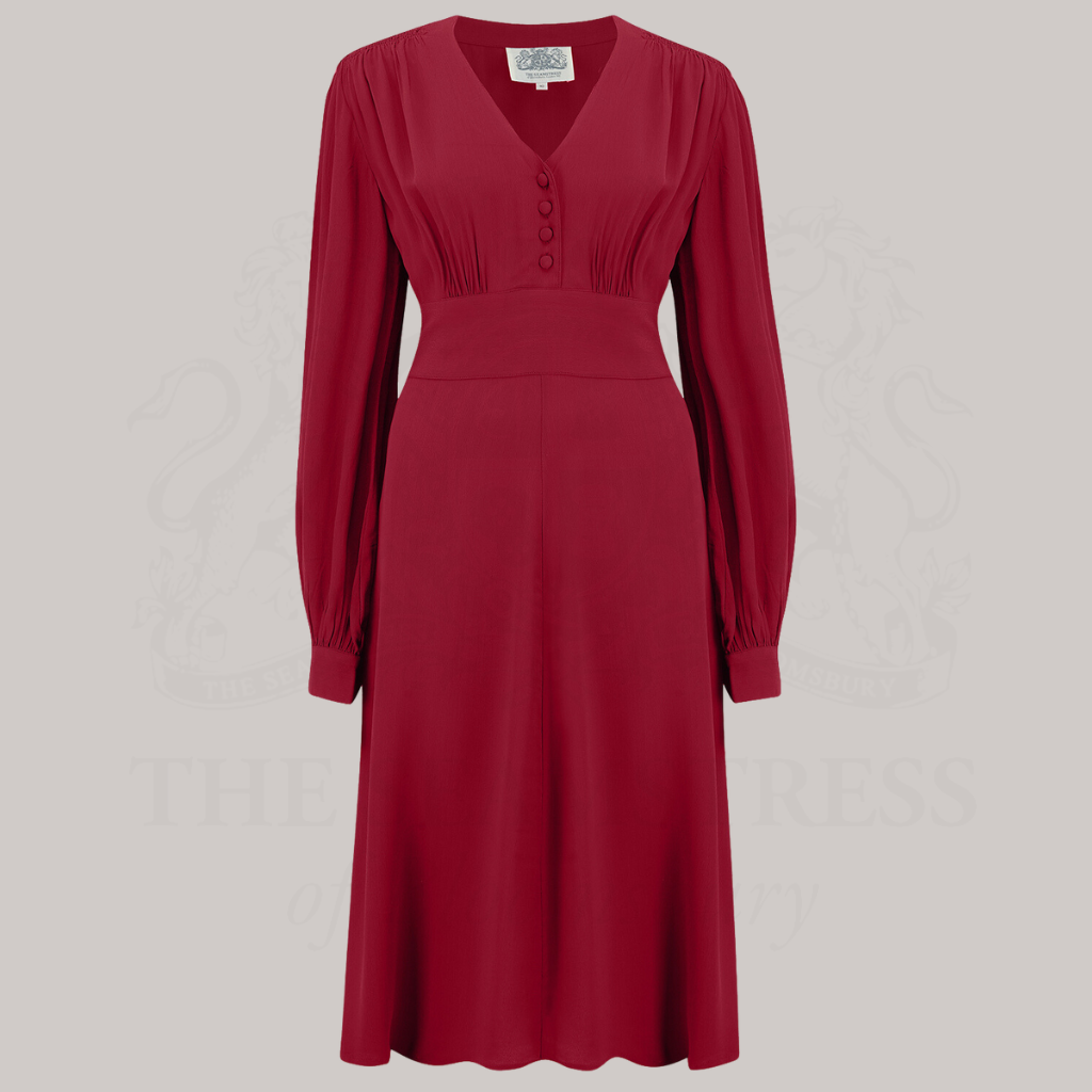 A 1940s-style long-sleeve dress in dark red/burgundy. Featuring gauged-in top yoke detailing on the shoulders and sleeves that puff out fully at the cuff. 