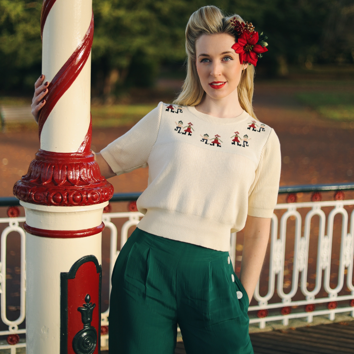 Model wears a cream short sleeve pullover jumper paired with green trousers.