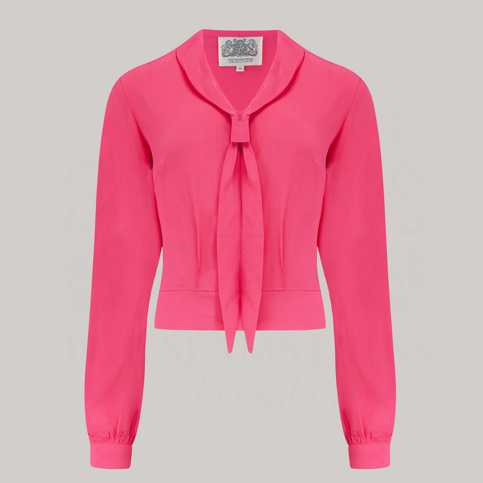 Model wears a long-sleeved raspberry pink blouse with a sailor-style collar.
