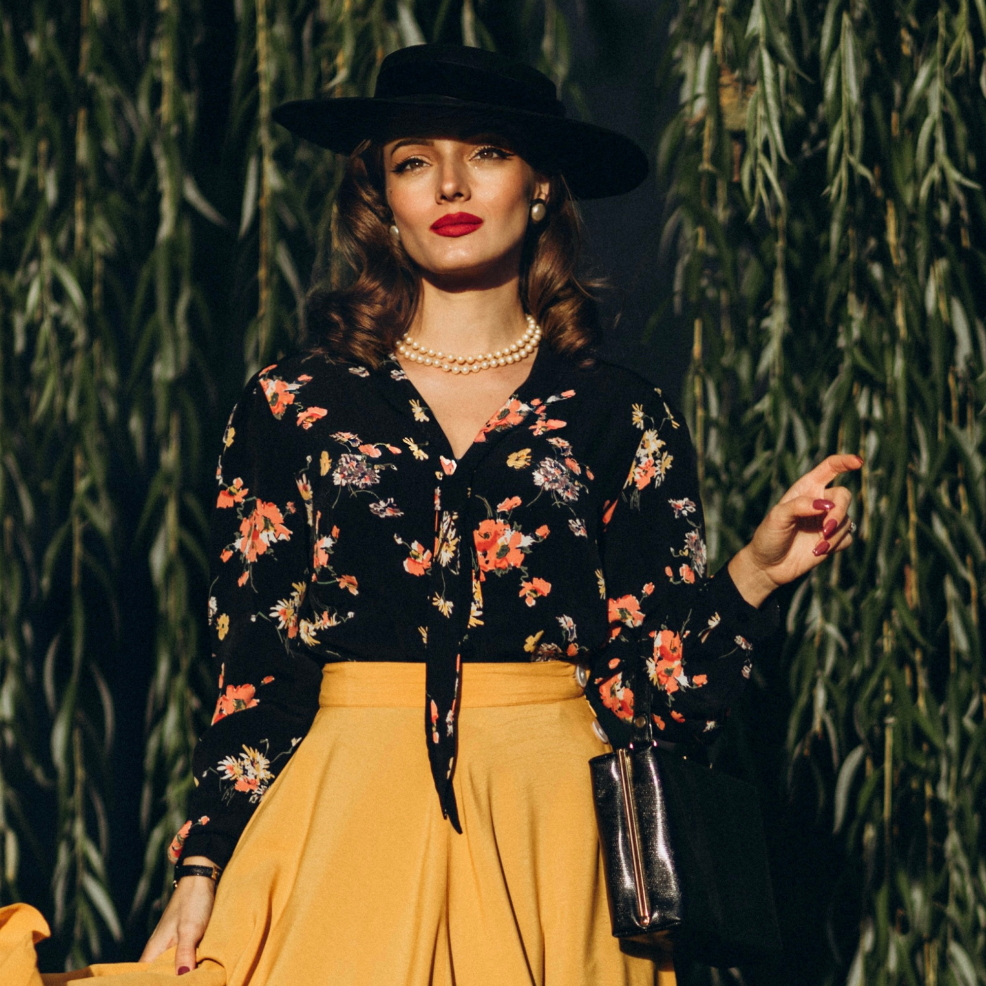 Model wears a long sleeve floral blouse with a sailor style collar.
