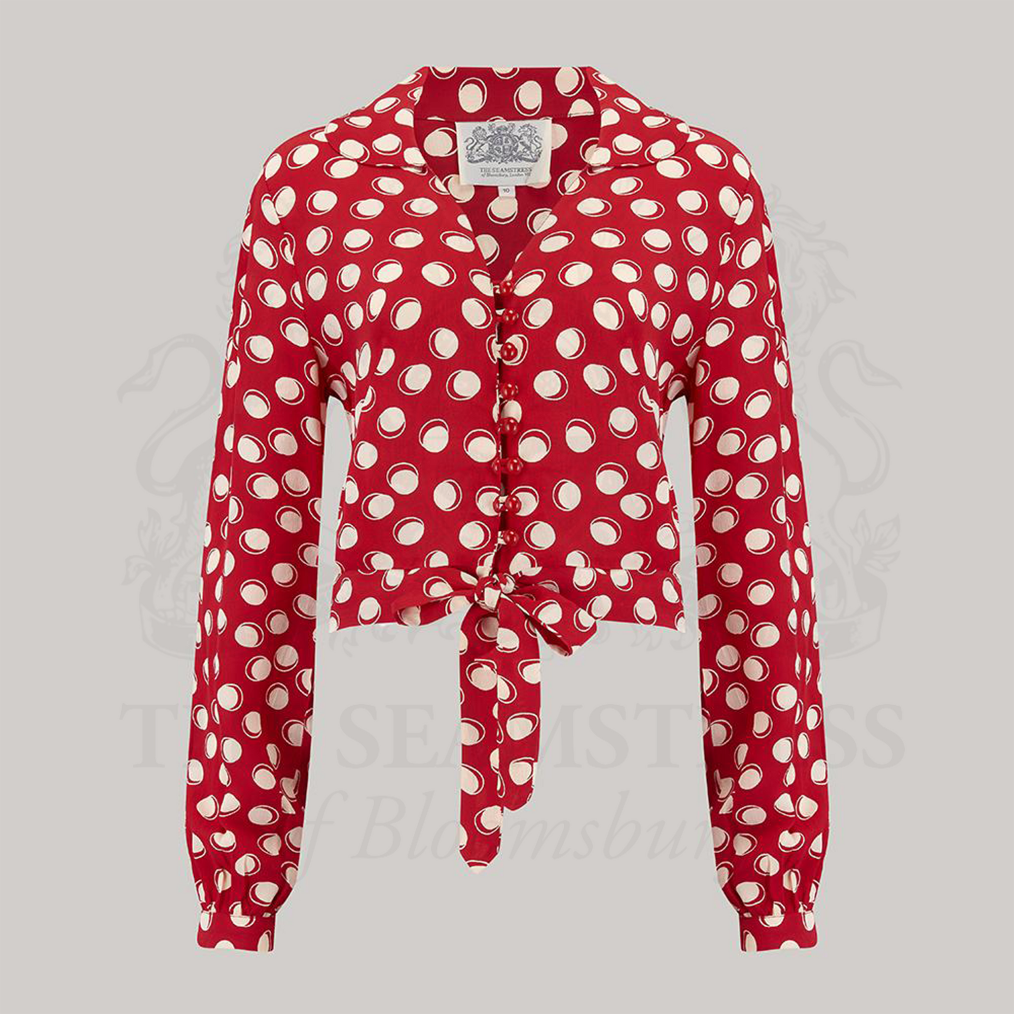 A  red and white polka dot blouse with long sleeves and a round neckline