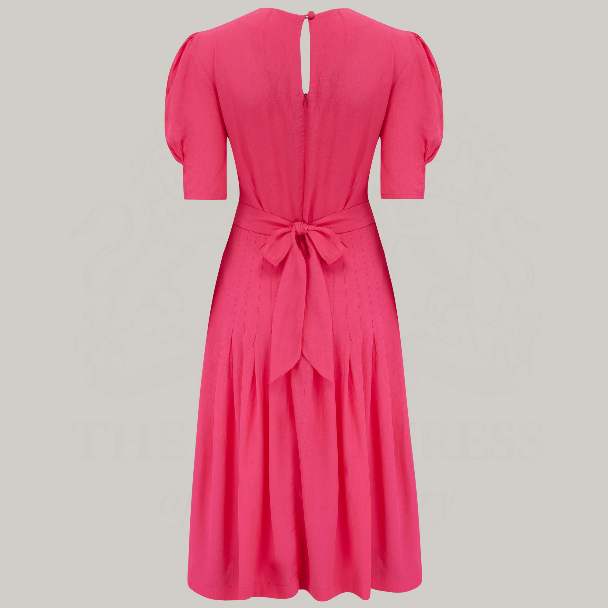 A 1940s-style short-sleeve dress in raspberry pink. Featuring a sweetheart neckline, smocking detailing, pockets, and a waist tie.
