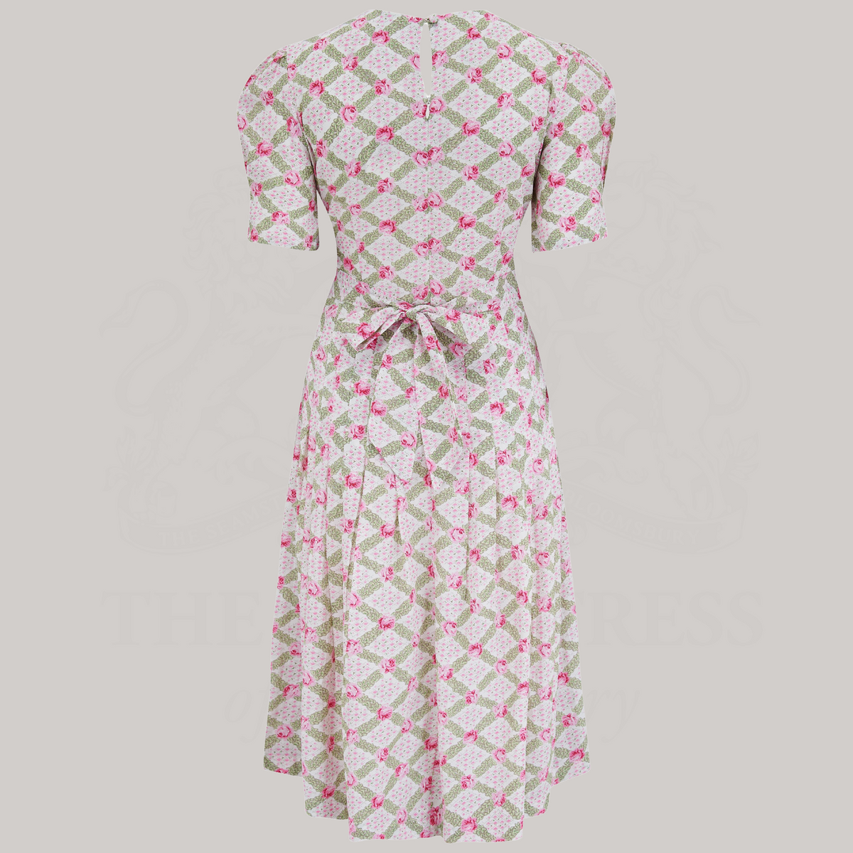 A 1940s-style short-sleeve dress in pink and cream floral. Featuring a sweetheart neckline, smocking detailing, pockets, and a waist tie.
