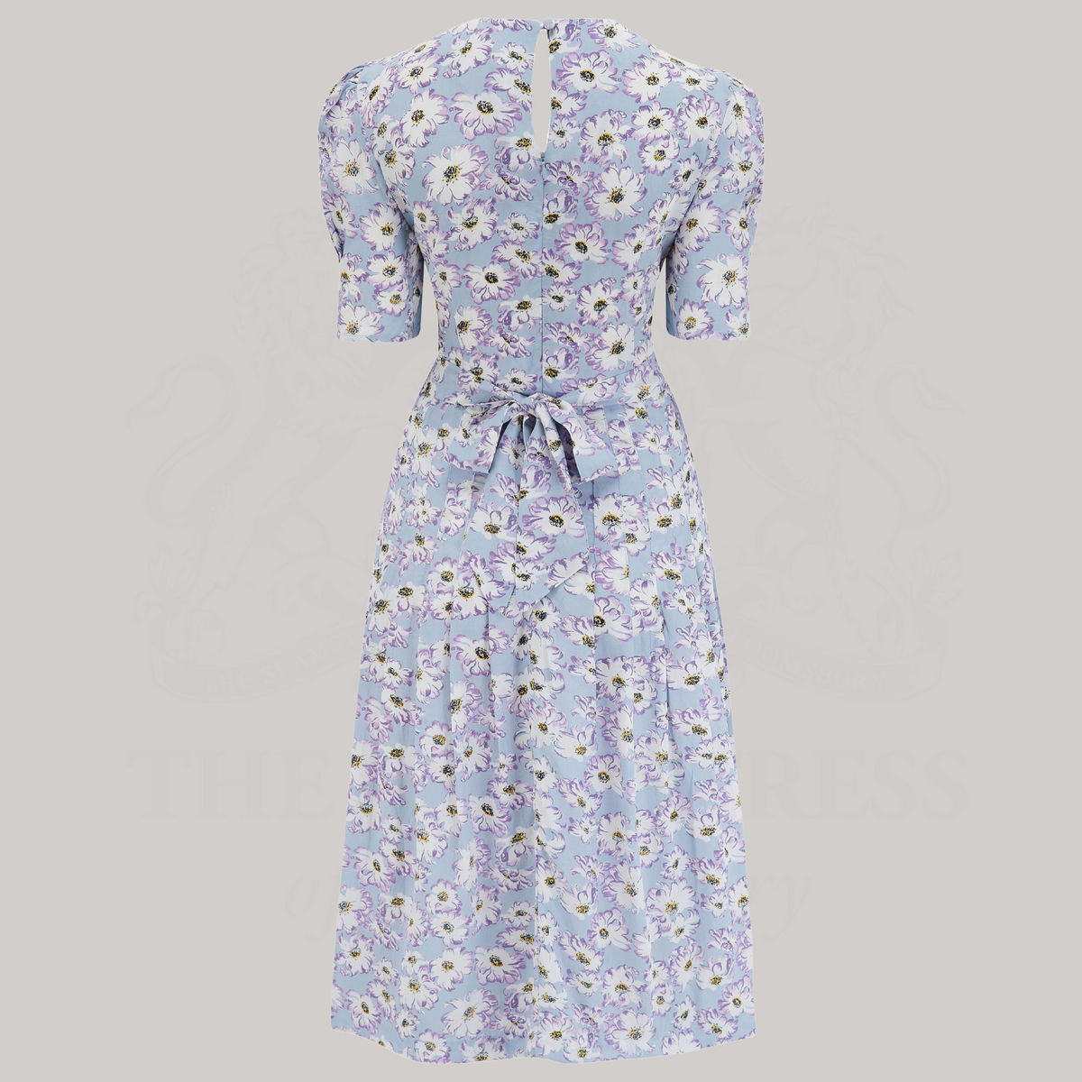 A 1940s-style short-sleeve dress in pale blue with floral design. Featuring a sweetheart neckline, smocking detailing, pockets, and a waist tie.