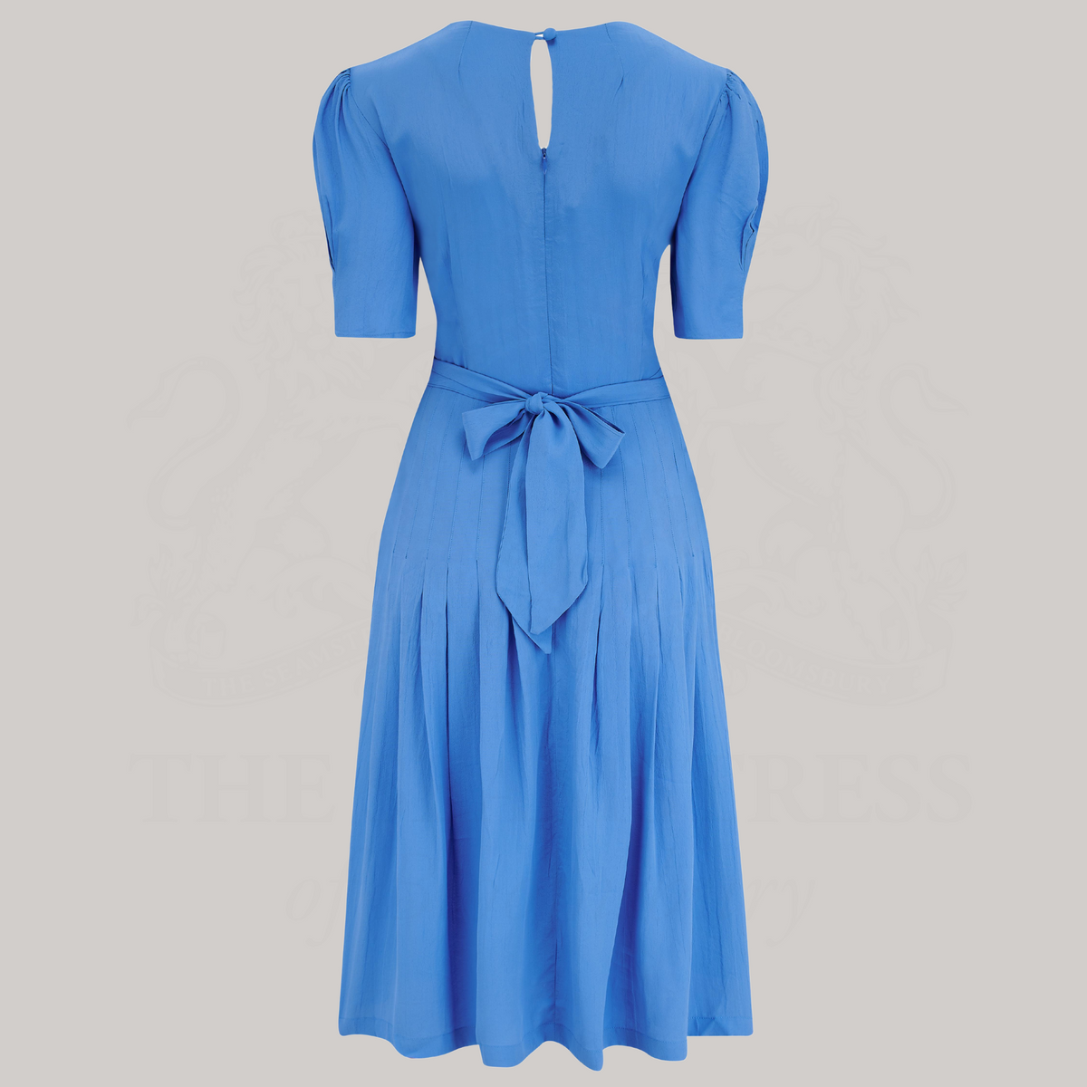 A 1940s-style short-sleeve dress in blue. Featuring a sweetheart neckline, smocking detailing, pockets, and a waist tie.
