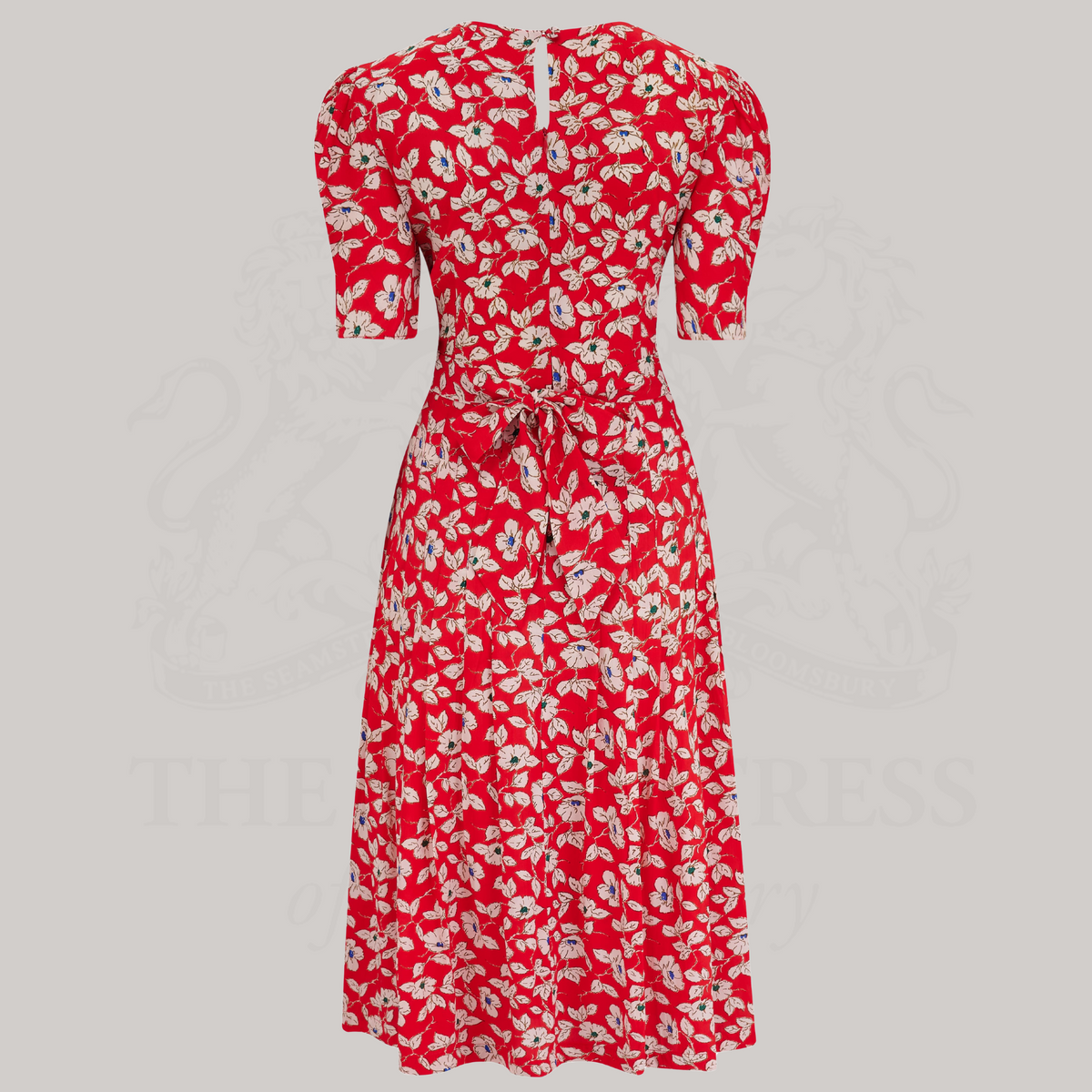 A 1940s-style short-sleeve dress in red with floral design. Featuring a sweetheart neckline, smocking detailing, pockets, and a waist tie.
