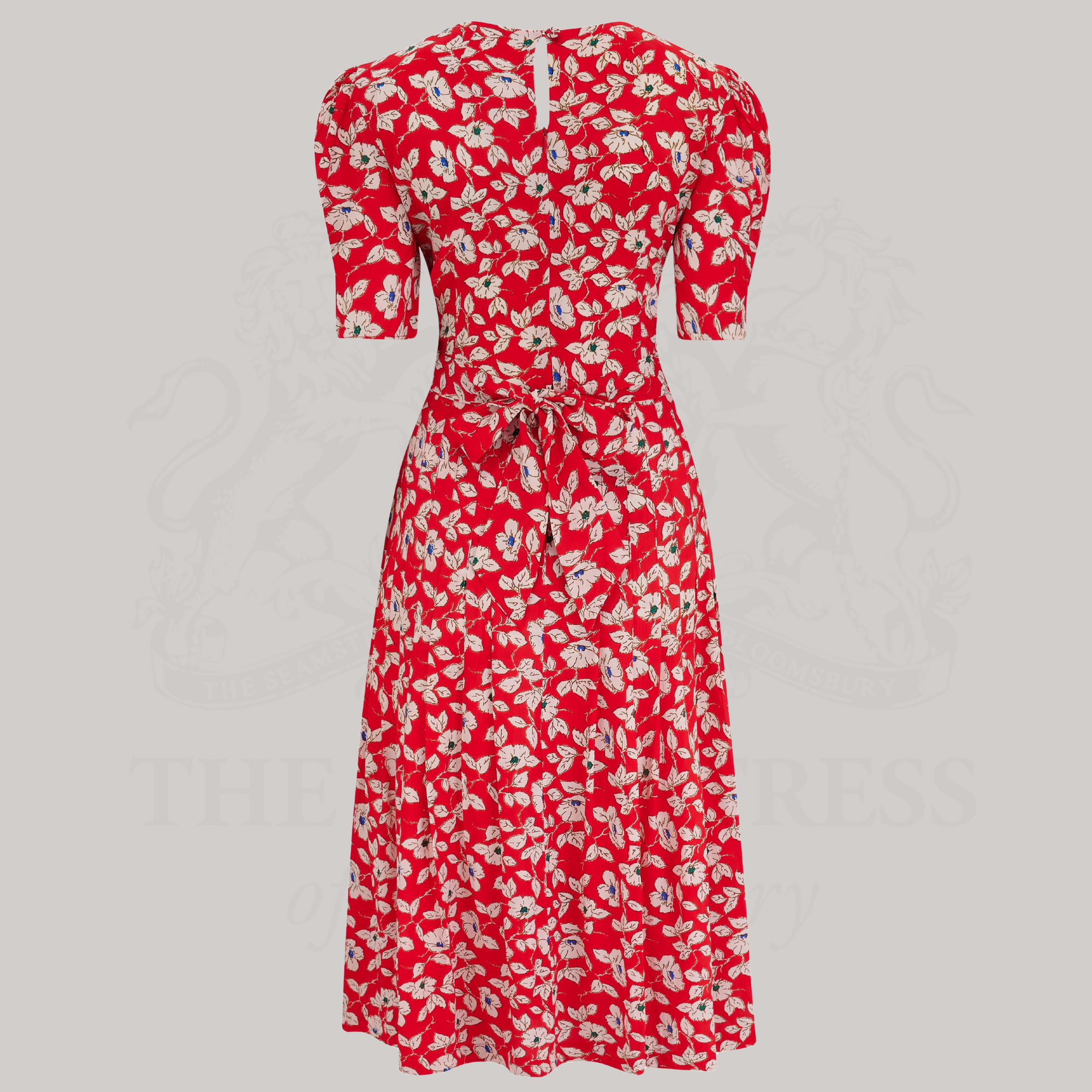 A 1940s-style short-sleeve dress in red with floral design. Featuring a sweetheart neckline, smocking detailing, pockets, and a waist tie.
