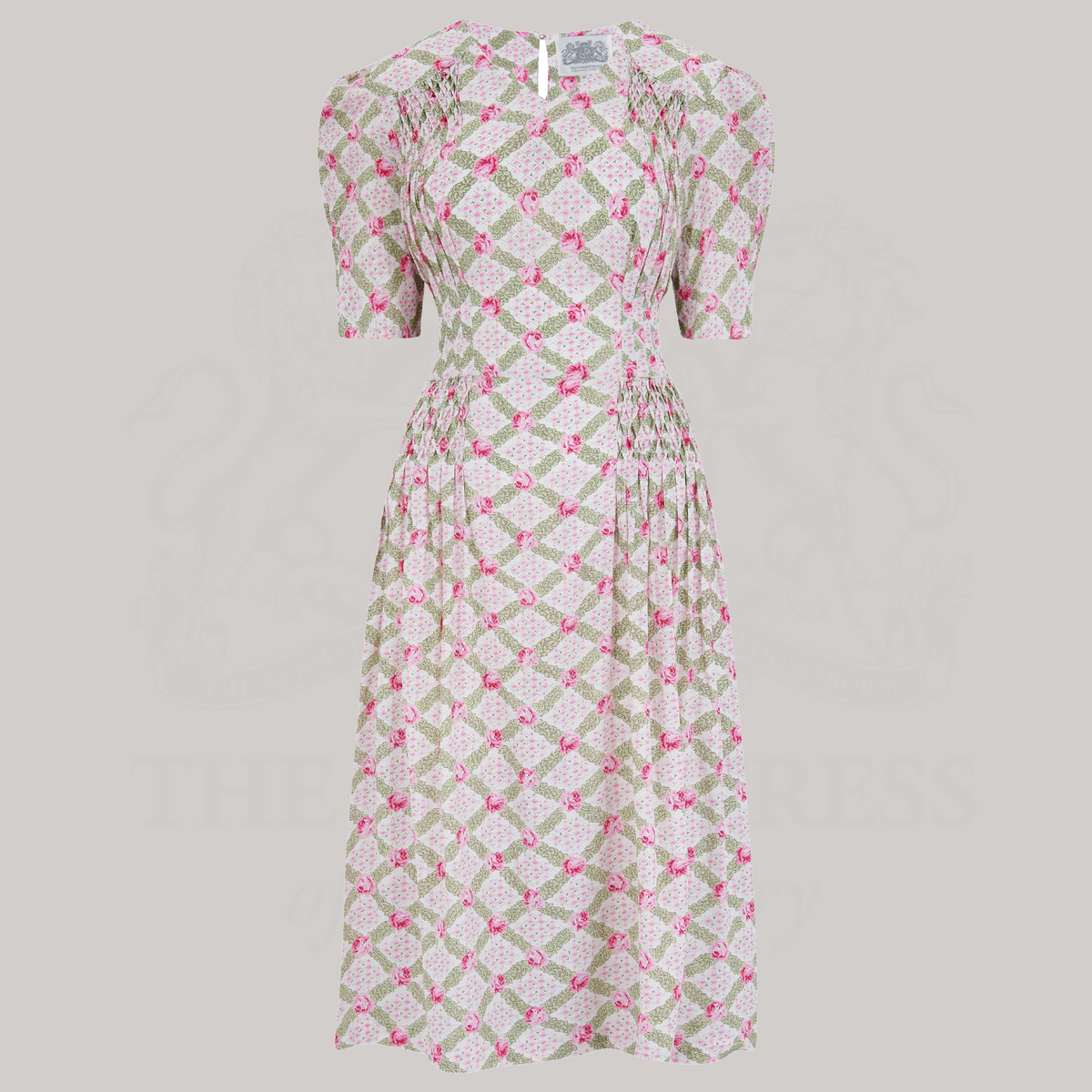 A 1940s-style short-sleeve dress in pink and cream floral. Featuring a sweetheart neckline, smocking detailing, pockets, and a waist tie.
