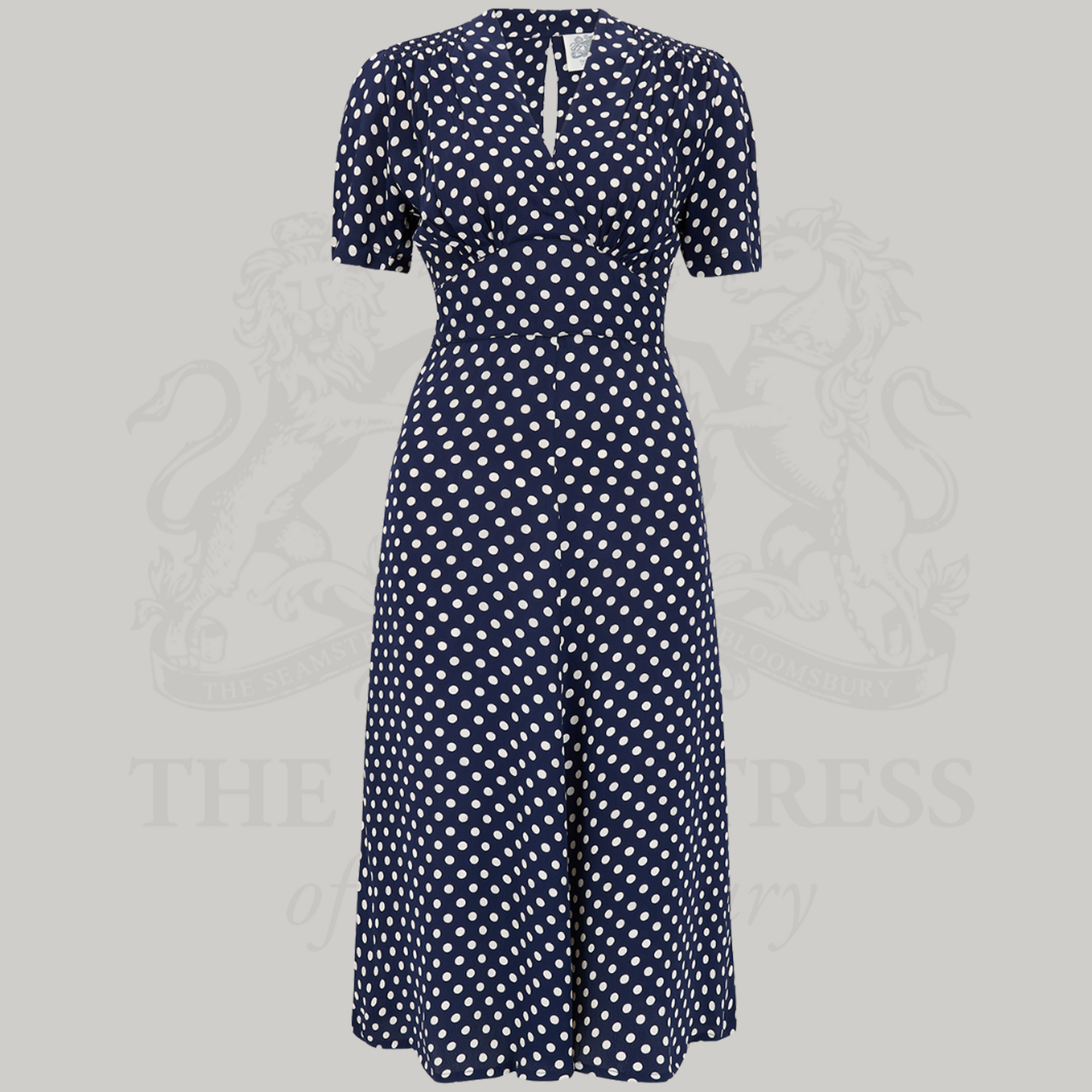A navy polka dot dress with long sleeves, featuring a v-neck and side pockets