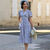 Model wears a 1940s-style tea dress in pale blue with a cream floral design, with matching cream gloves.