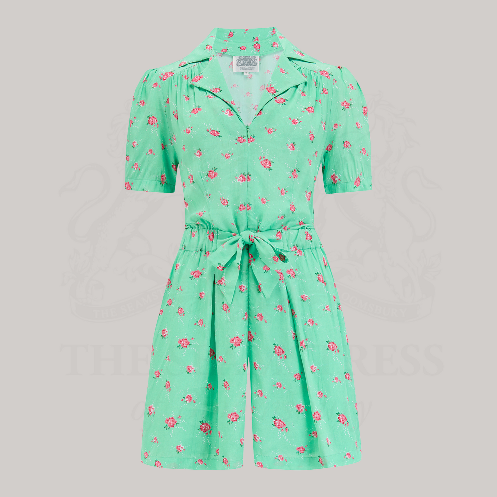 A 1940s-style playsuit in a mint green colour with floral design. Playsuit has a zip down the front, short sleeves, and short legs.