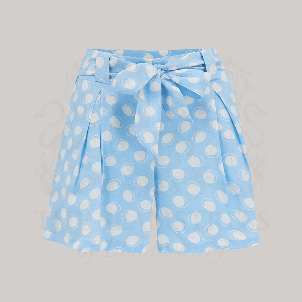 A pair of sky blue shorts with a large white polka dot pattern, featuring a side zip and an adjustable tie-waist belt.