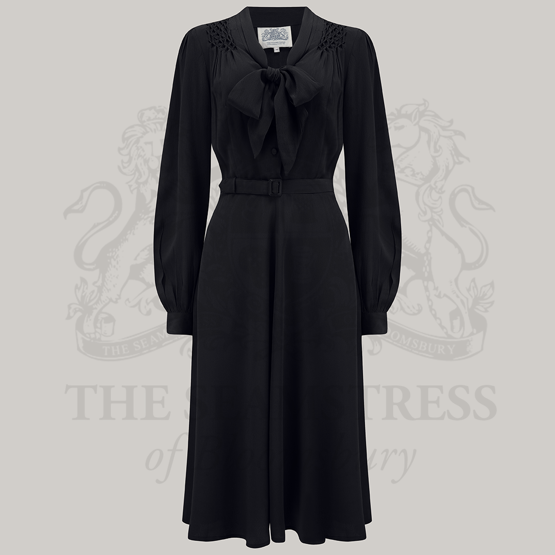 A  vintage-inspired black dress with a pussy-bow neckline, long sleeves, and smock stitching on the shoulders.