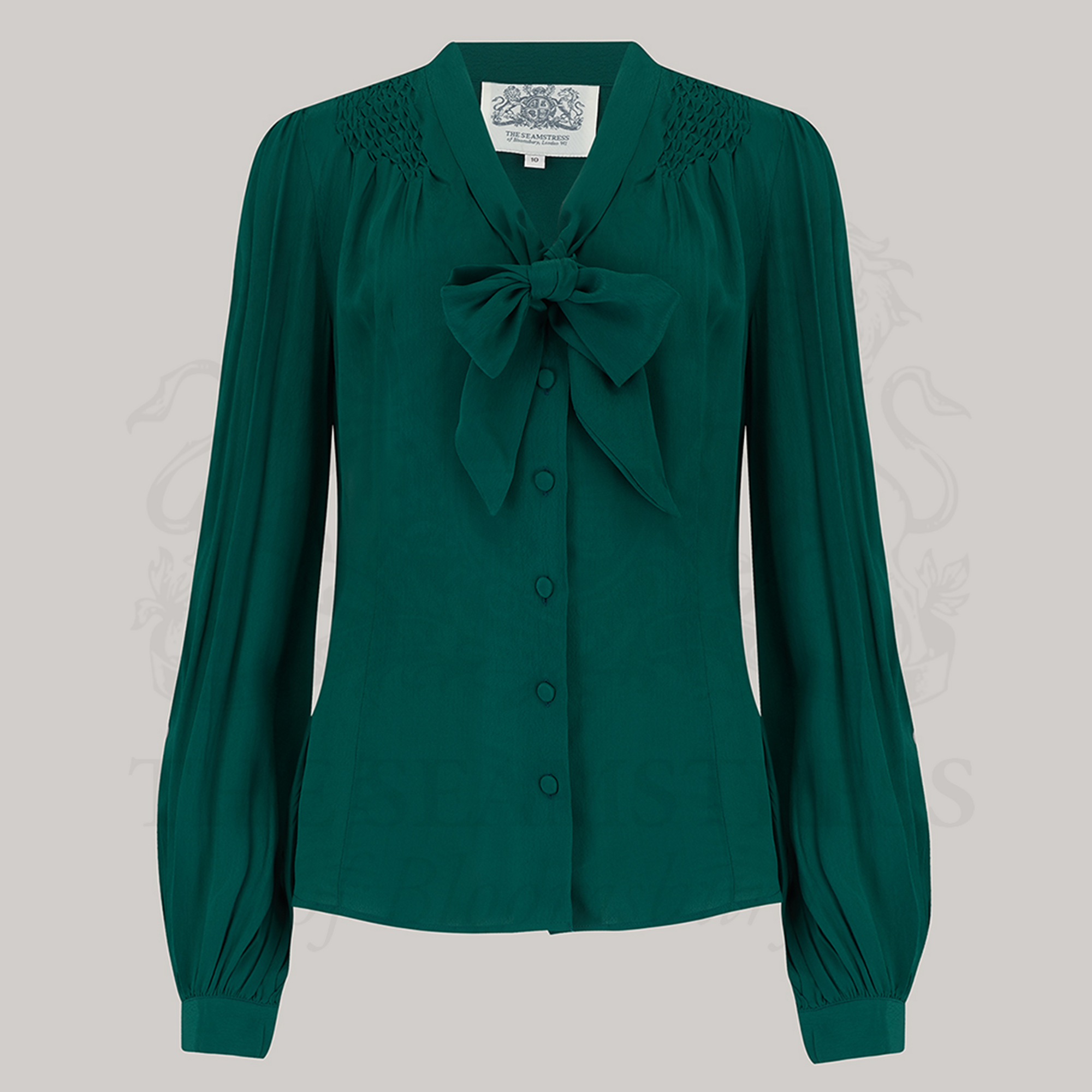 A vintage-inspired green blouse with a pussy-bow neckline, long bishop sleeves with full cuffs, and smock stitching on shoulders, button fastenings.