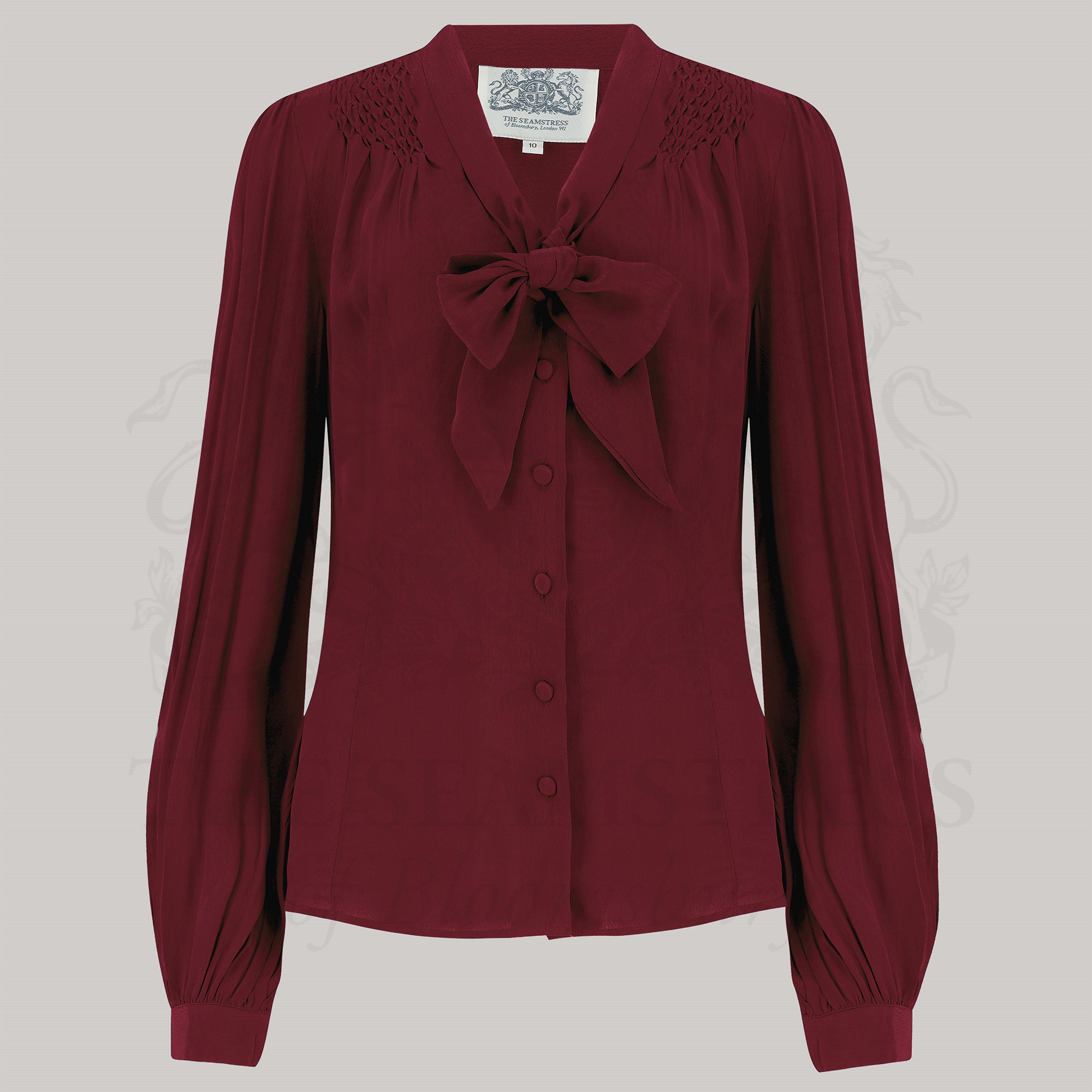 A person wearing a red Eva pussy-bow blouse with long bishop sleeves and button fastenings, made of Crepe de Chine fabric.