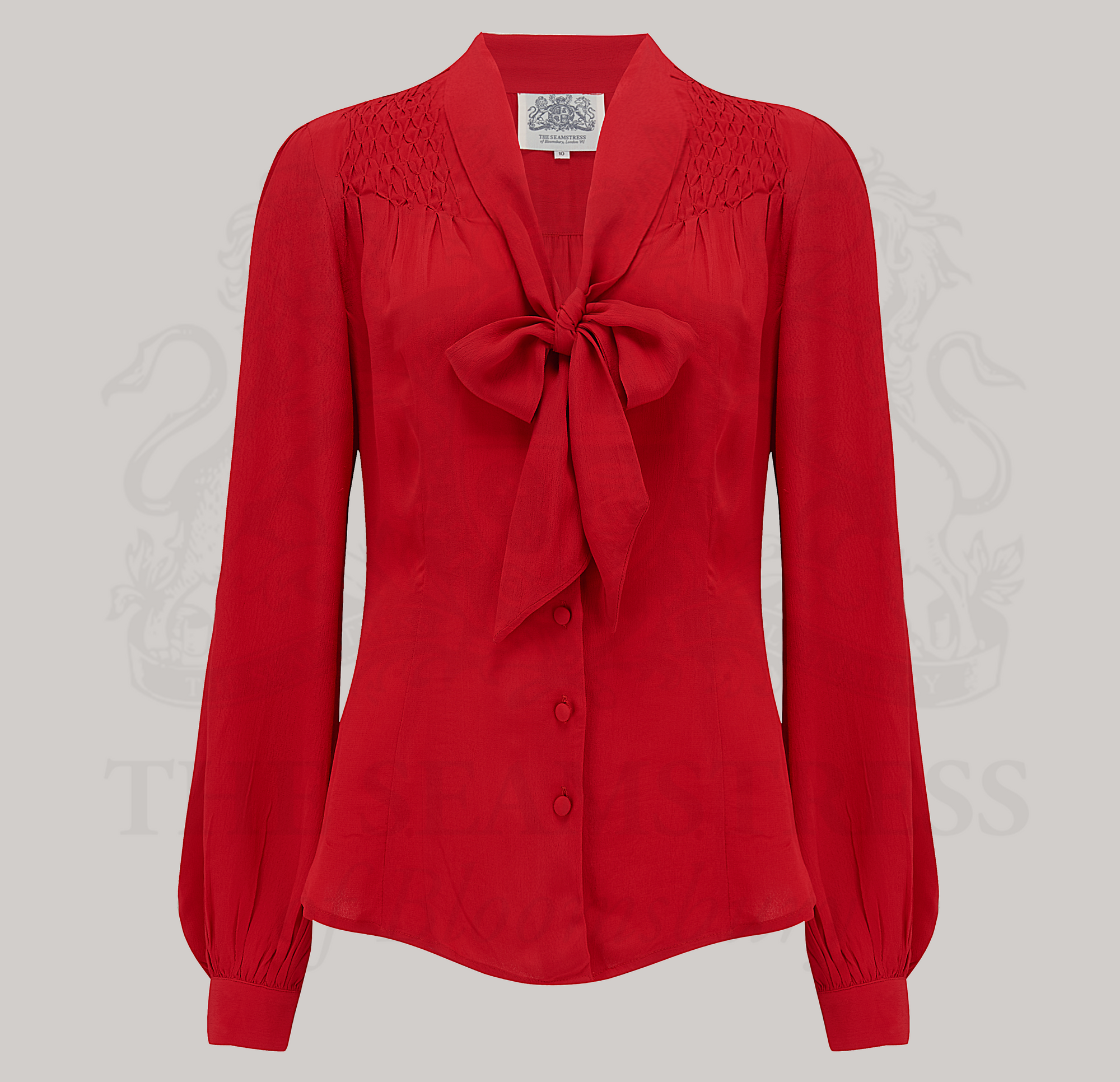 A vintage-inspired red blouse with a pussy-bow neckline, long bishop sleeves with full cuffs, and smock stitching on shoulders, button fastenings.