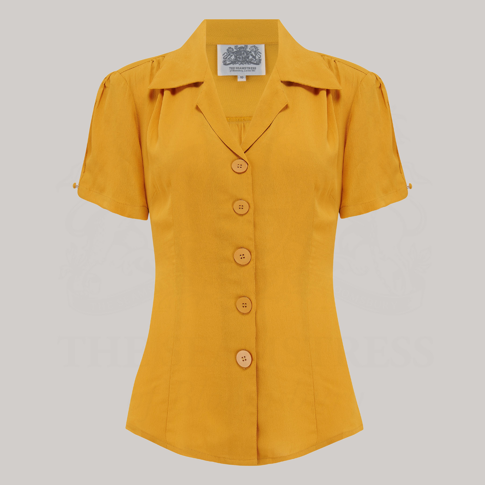 A mustard yellow blouse with a classic revere collar, short sleeves, and large bakelite buttons.