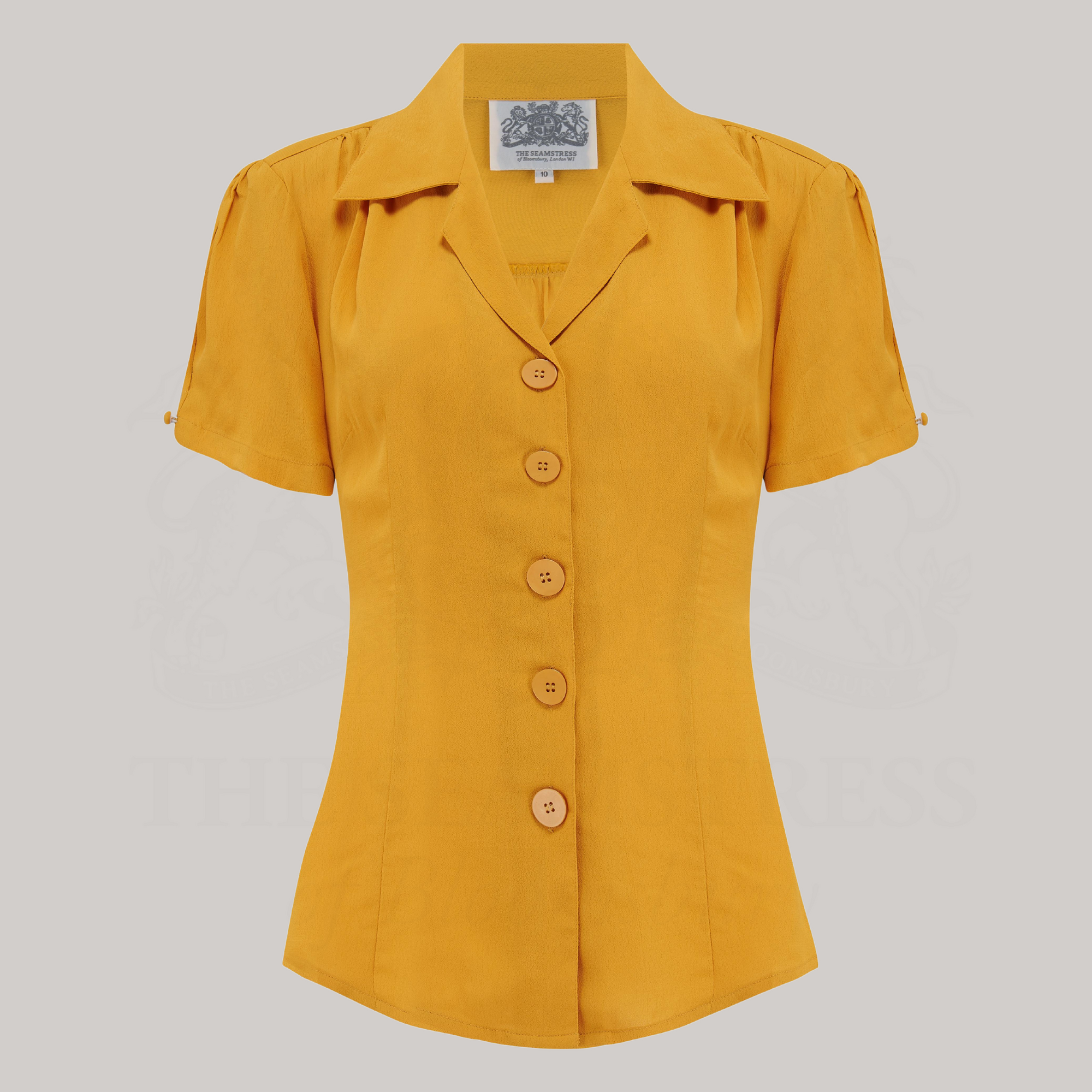 A mustard yellow blouse with a classic revere collar, short sleeves, and large bakelite buttons.