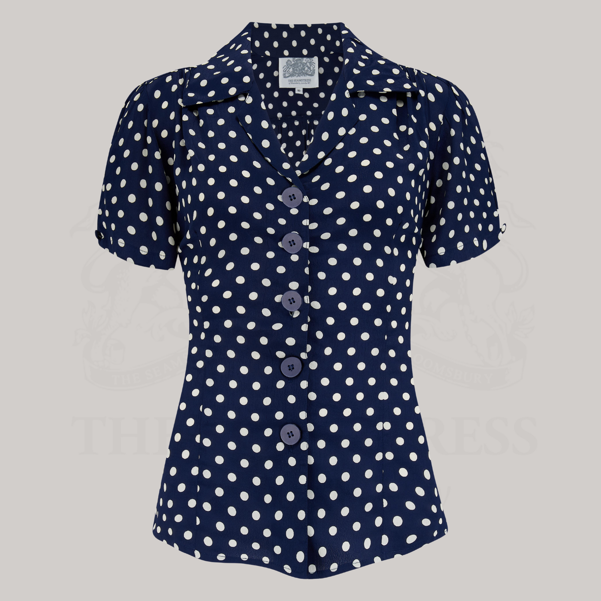 A navy crepe de chine blouse with white polka dots, featuring a classic revere collar, large bakelite buttons, and short sleeves.