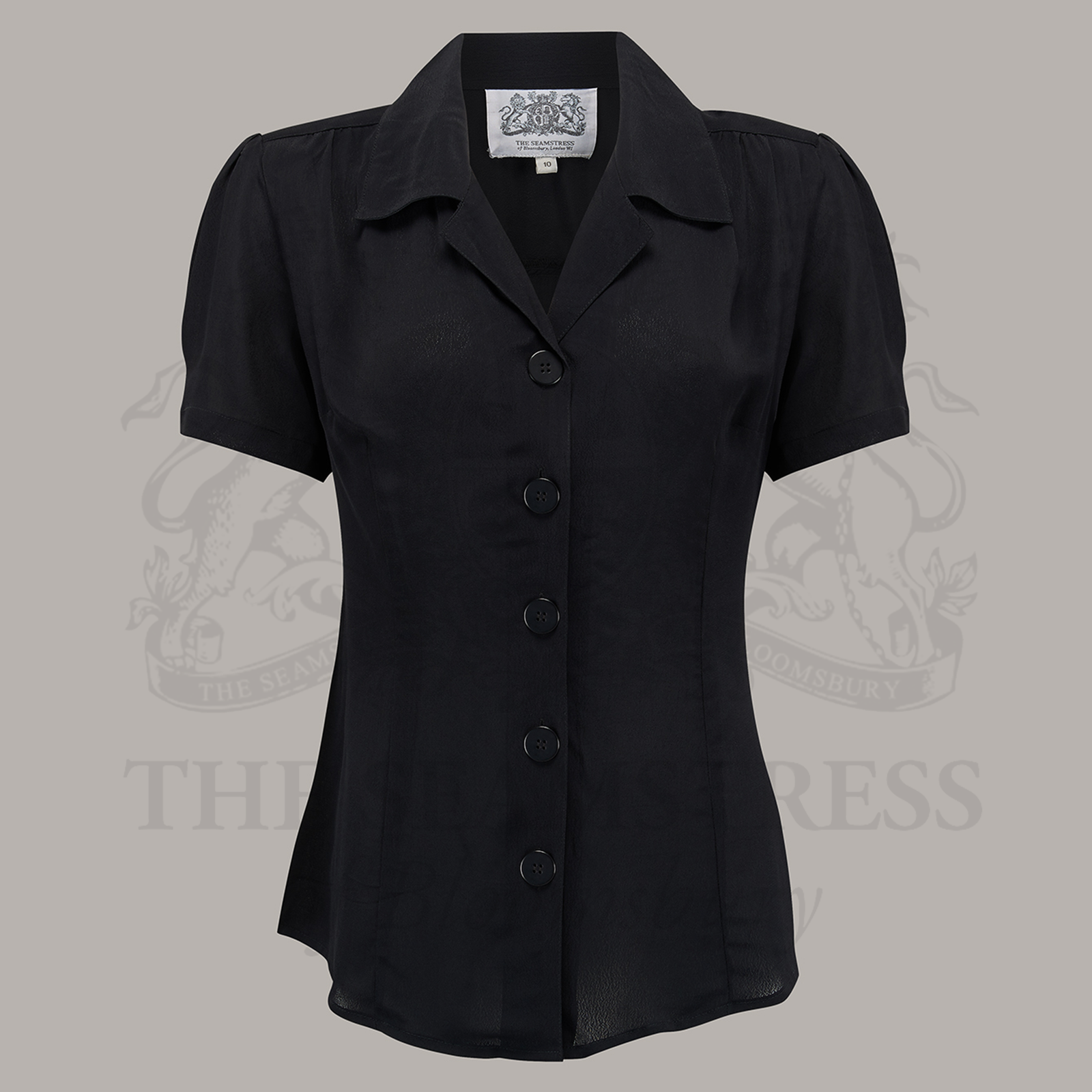 A black, short-sleeved blouse with a classic revere collar and large bakelite buttons