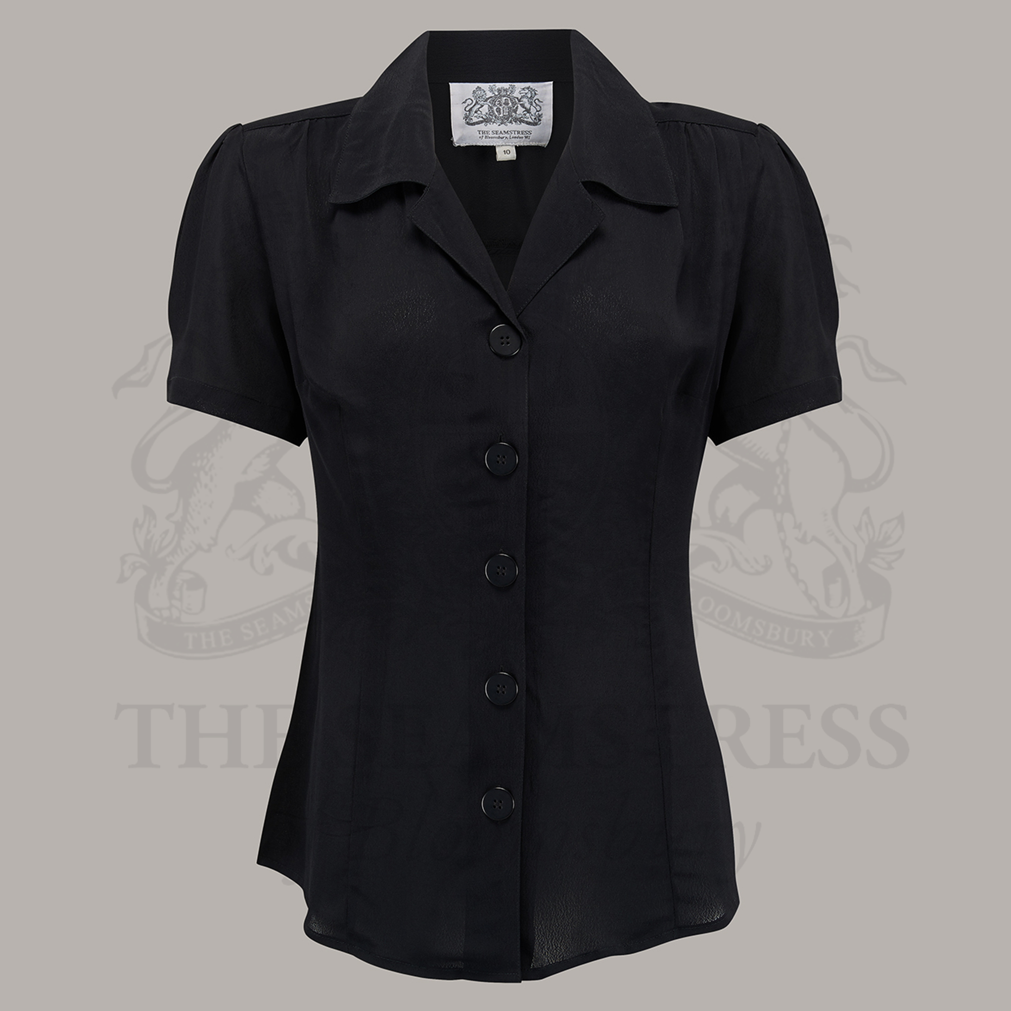 A black, short-sleeved blouse with a classic revere collar and large bakelite buttons
