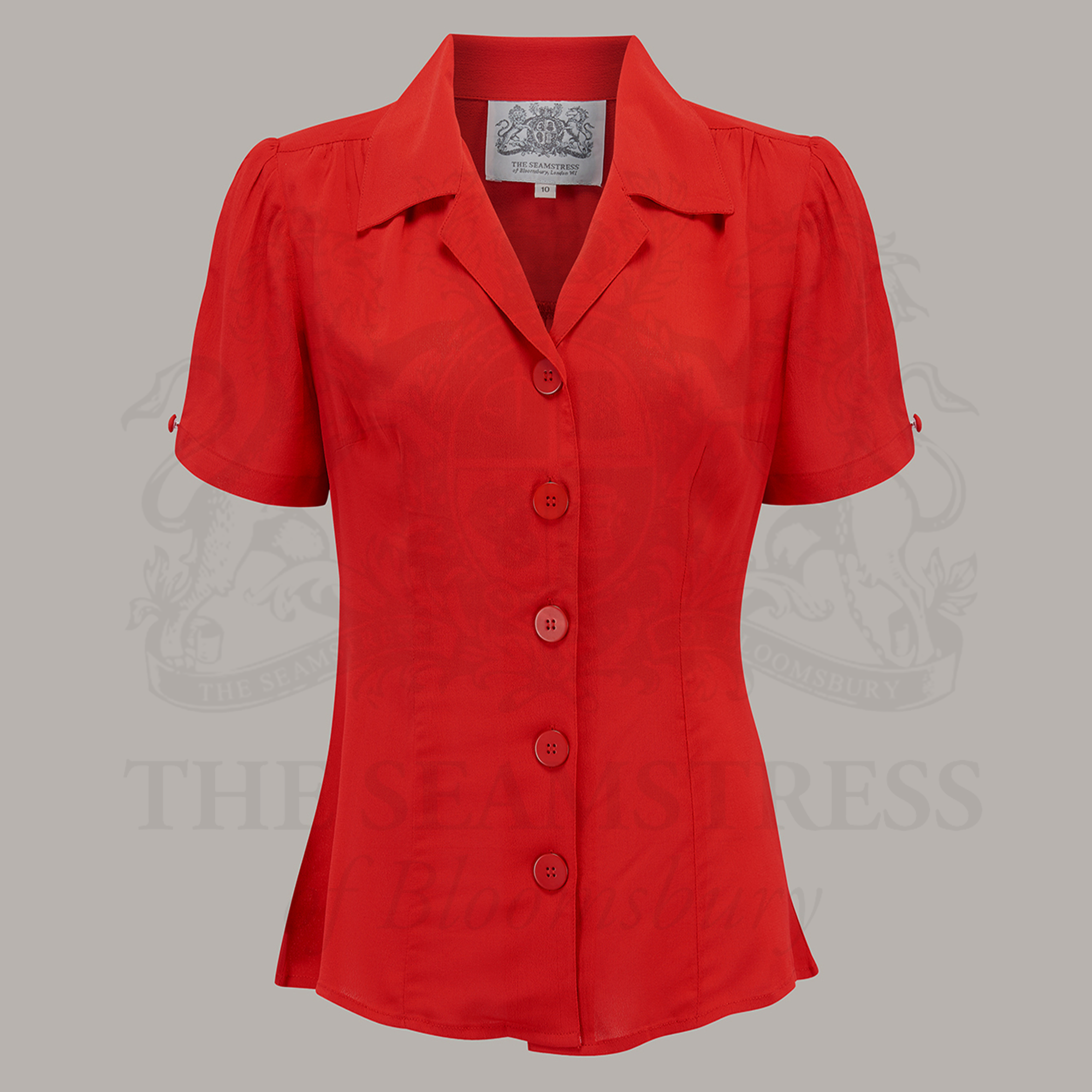 A red, short-sleeved blouse with a revere collar and large bakelite buttons.