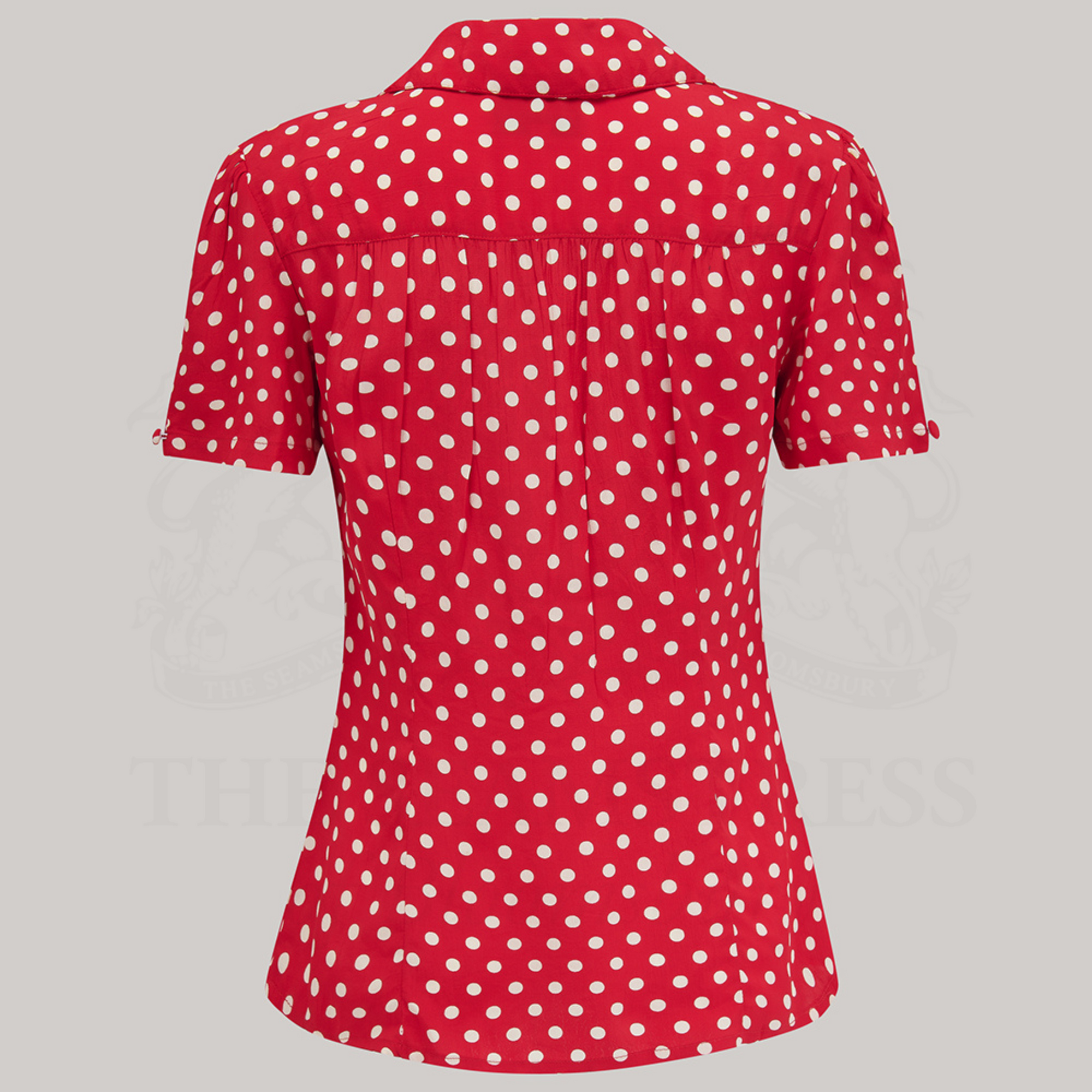 A red polka dot blouse with a classic revere collar, large bakelite buttons, and short sleeves.