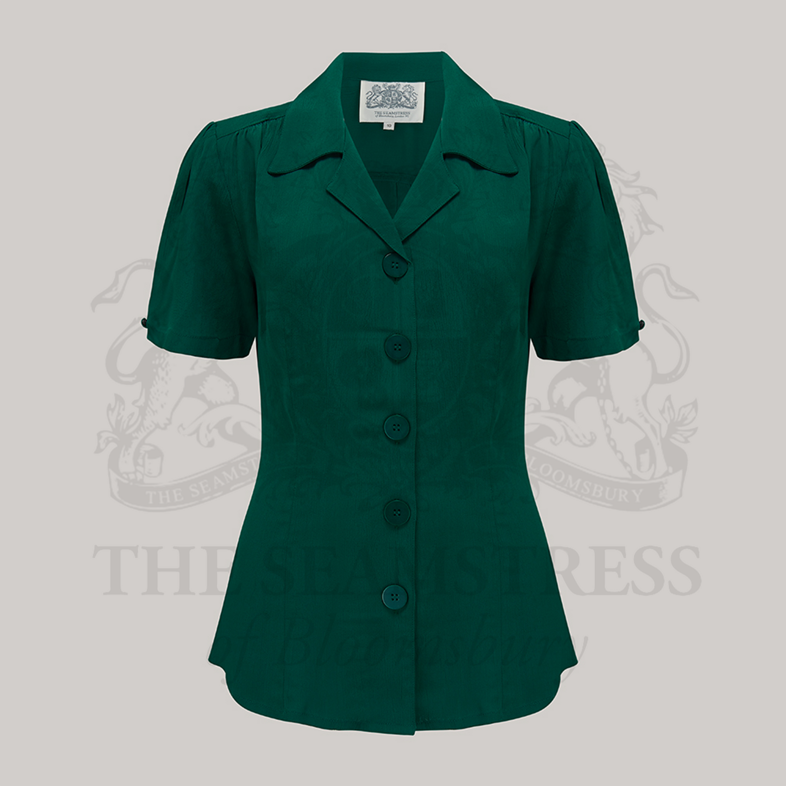 A green, short-sleeved blouse with a classic revere collar and large bakelite buttons.