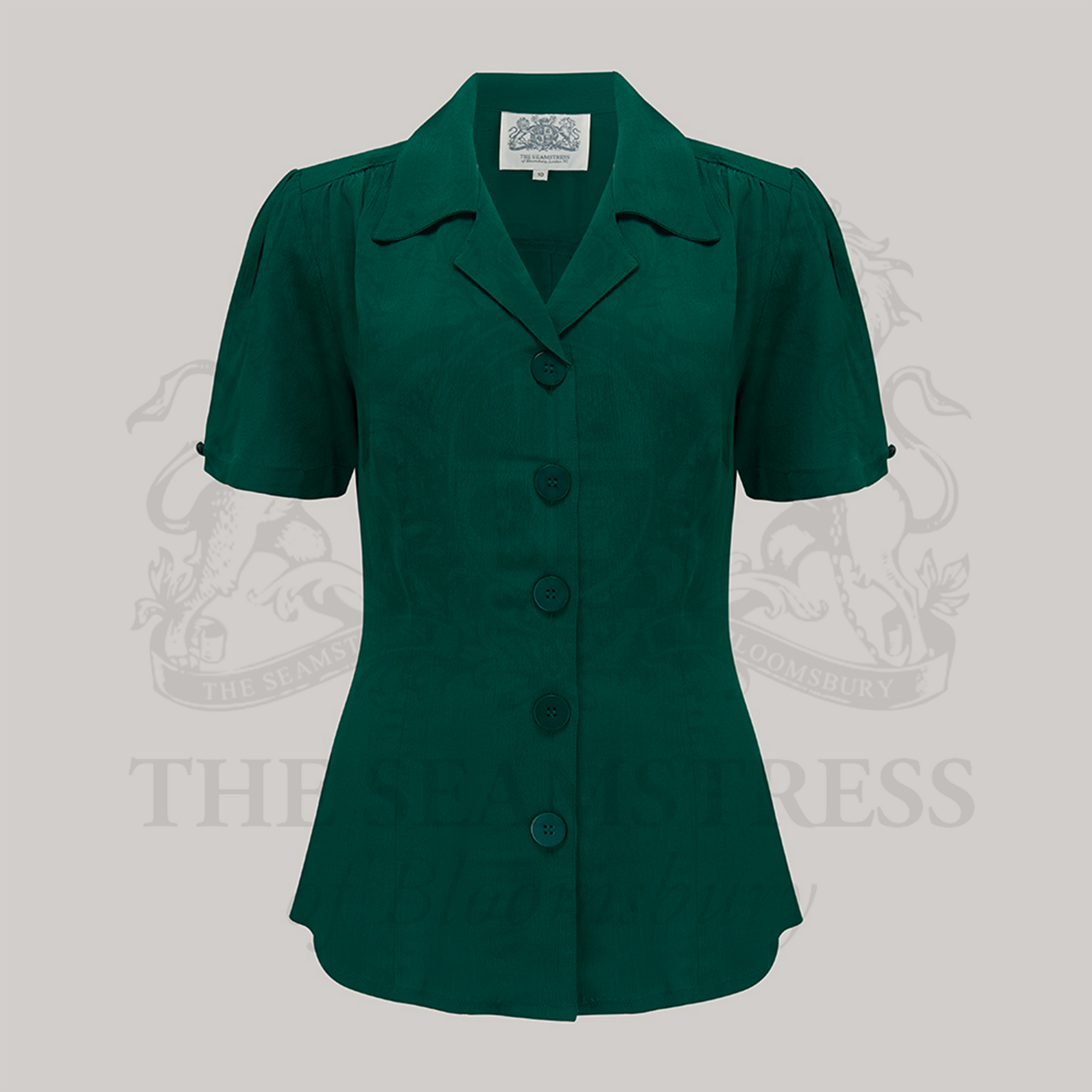 A green, short-sleeved blouse with a classic revere collar and large bakelite buttons.