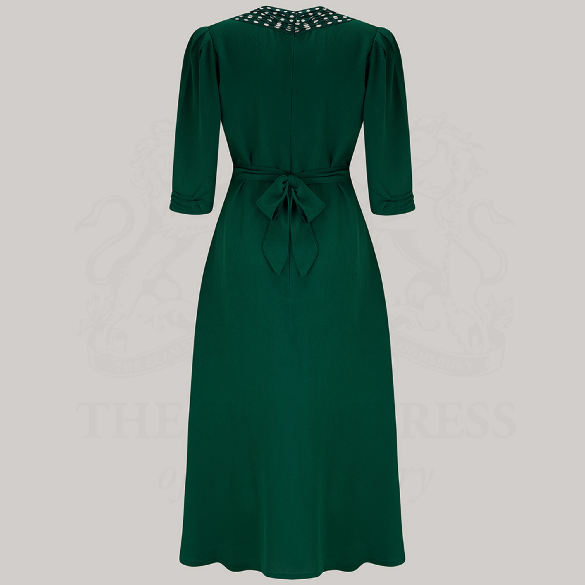 A Green dress with polka dots on the shoulders, featured on a grey background.