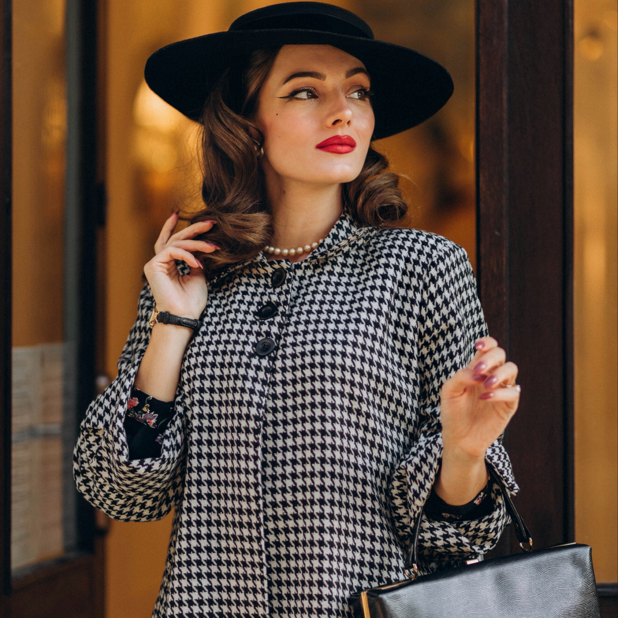 A woman wearing a vintage style swing jacket with a houndstooth pattern. The jacket features big turn-back cuffs and 3 big buttons at the front.