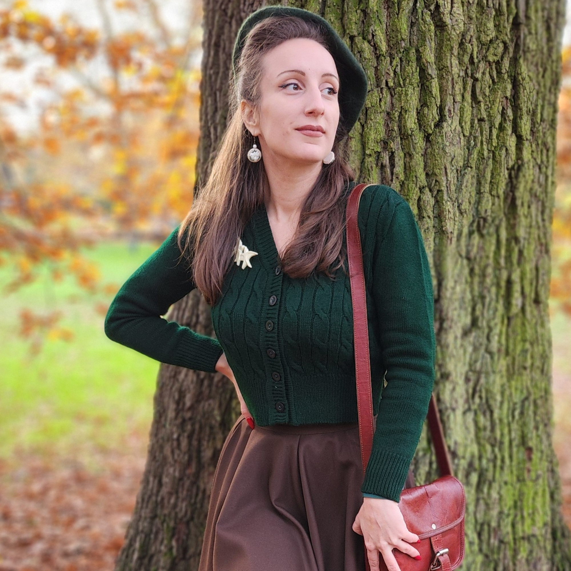 A 1940s style cable knitted cardigan in dark green. Matching coloured buttons feature down the front of the cardigan.