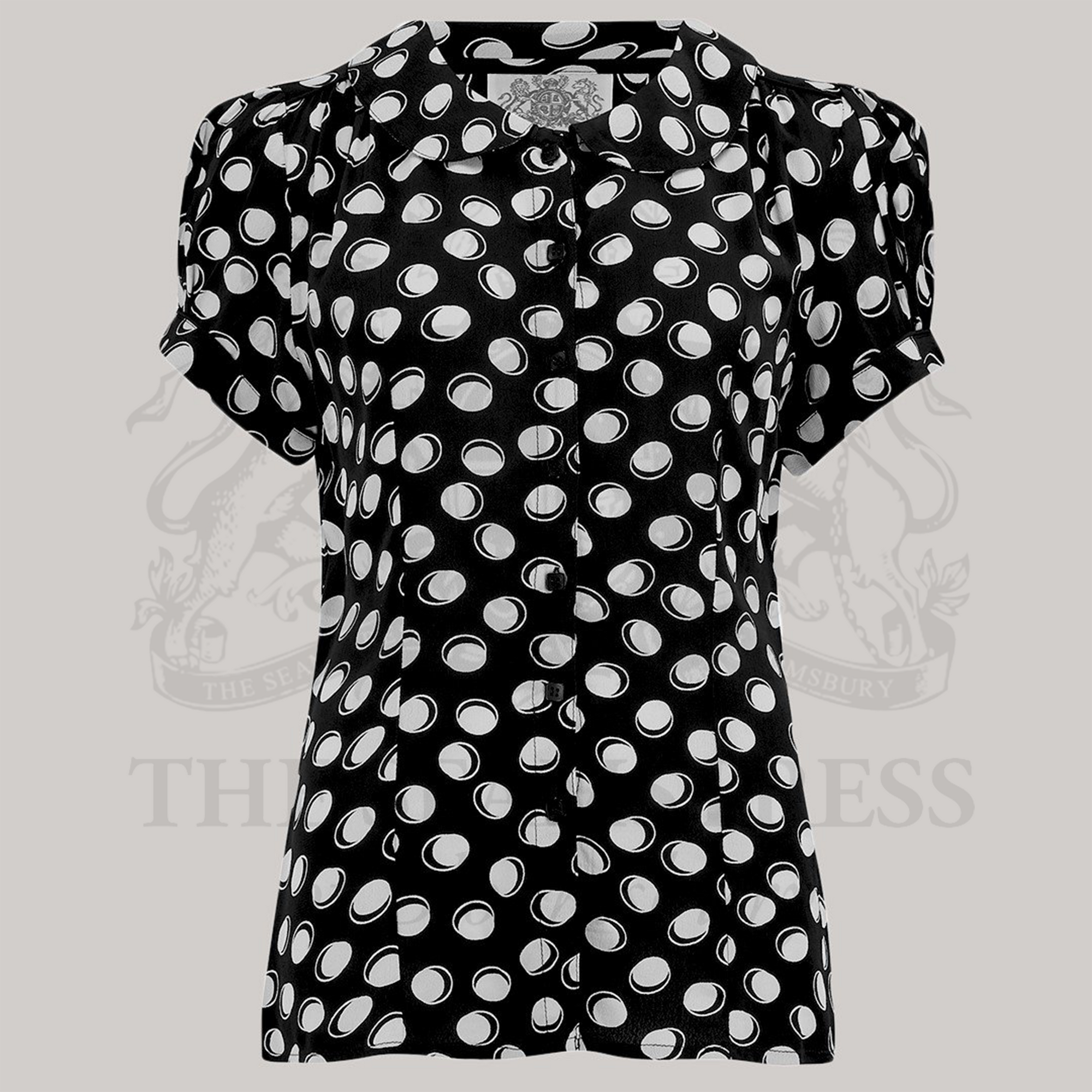 A short-sleeved black blouse with a Peter Pan collar and white polka dot pattern, featuring front button fastenings.