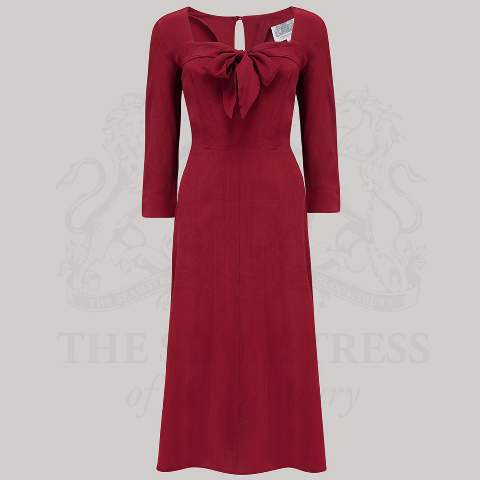 A red, long-sleeved, knee-length dress with a sweetheart neckline and a center front pussy bow.