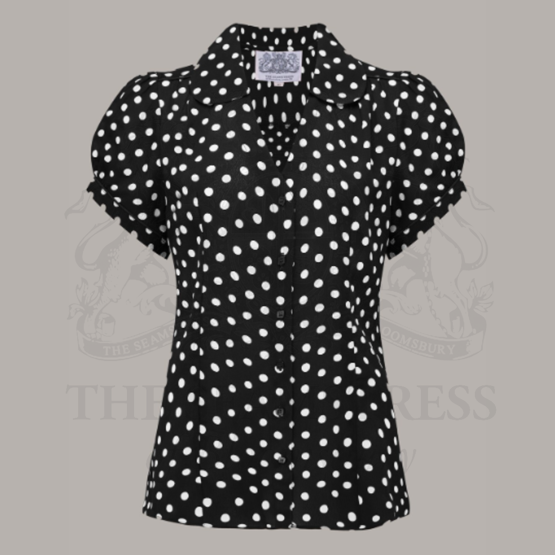 A black and white polka dot blouse with a Peter Pan-style collar and puff sleeves.