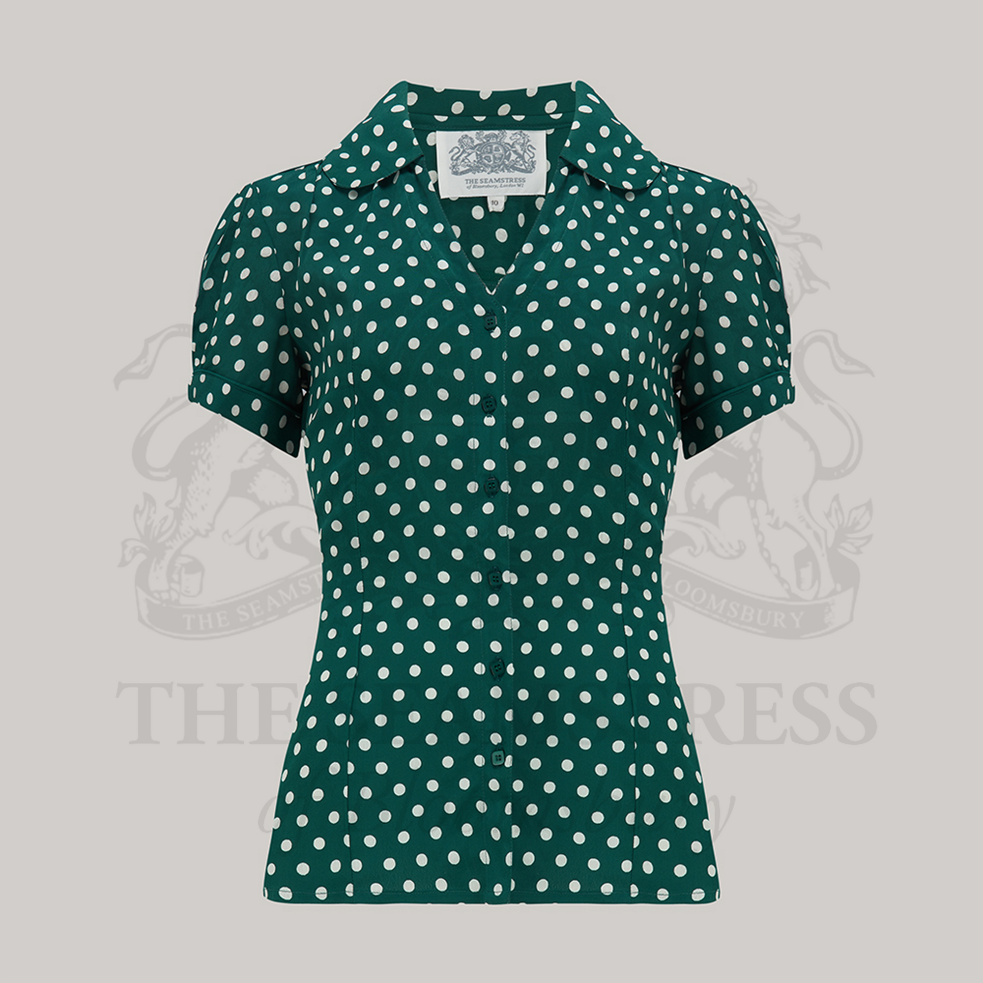 A vintage-style green blouse with white polka dots, featuring a Peter Pan-style collar and puff sleeves.